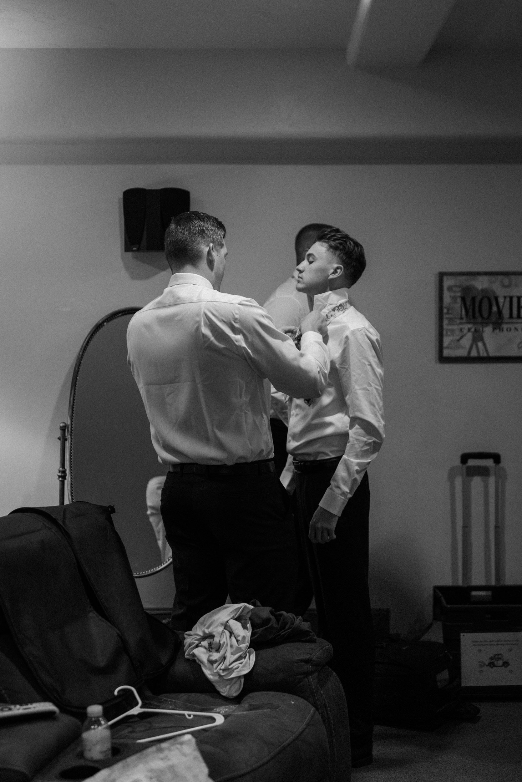 The groom helps a groomsmen tie their tie