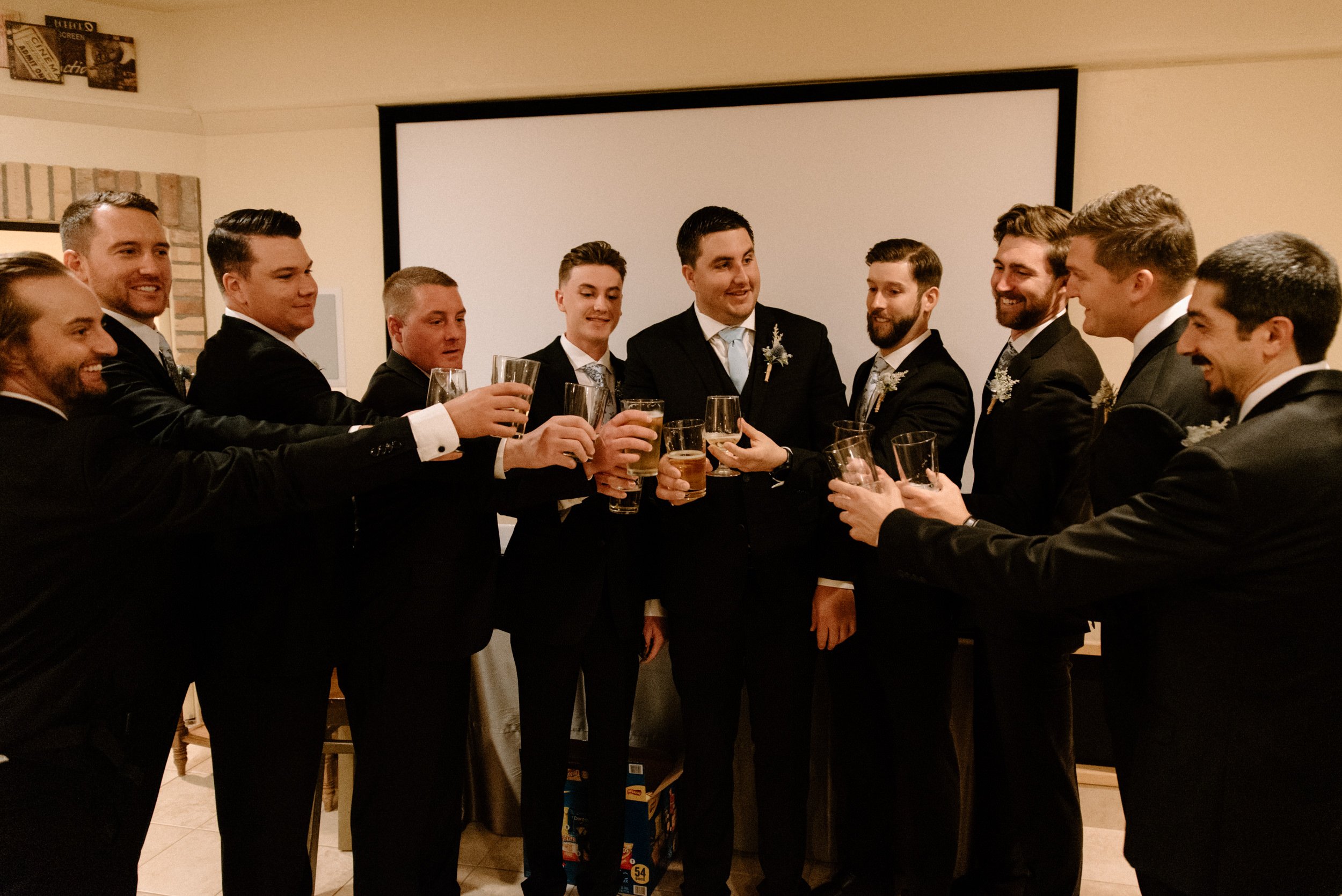 The groomsmen lift their beer glasses in toast