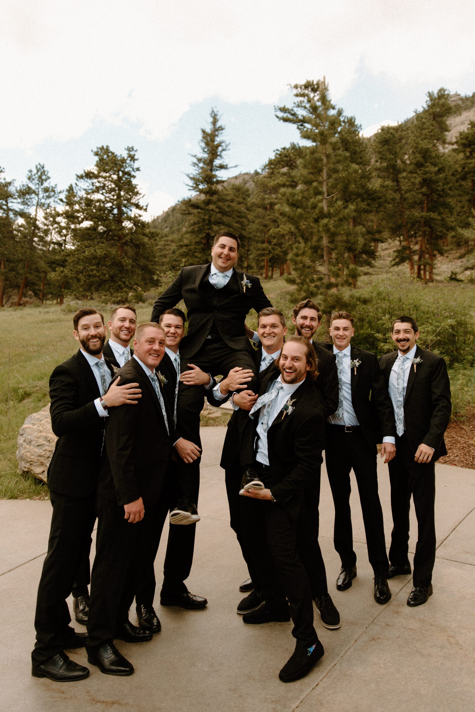 The groomsmen lift the groom up and laugh together