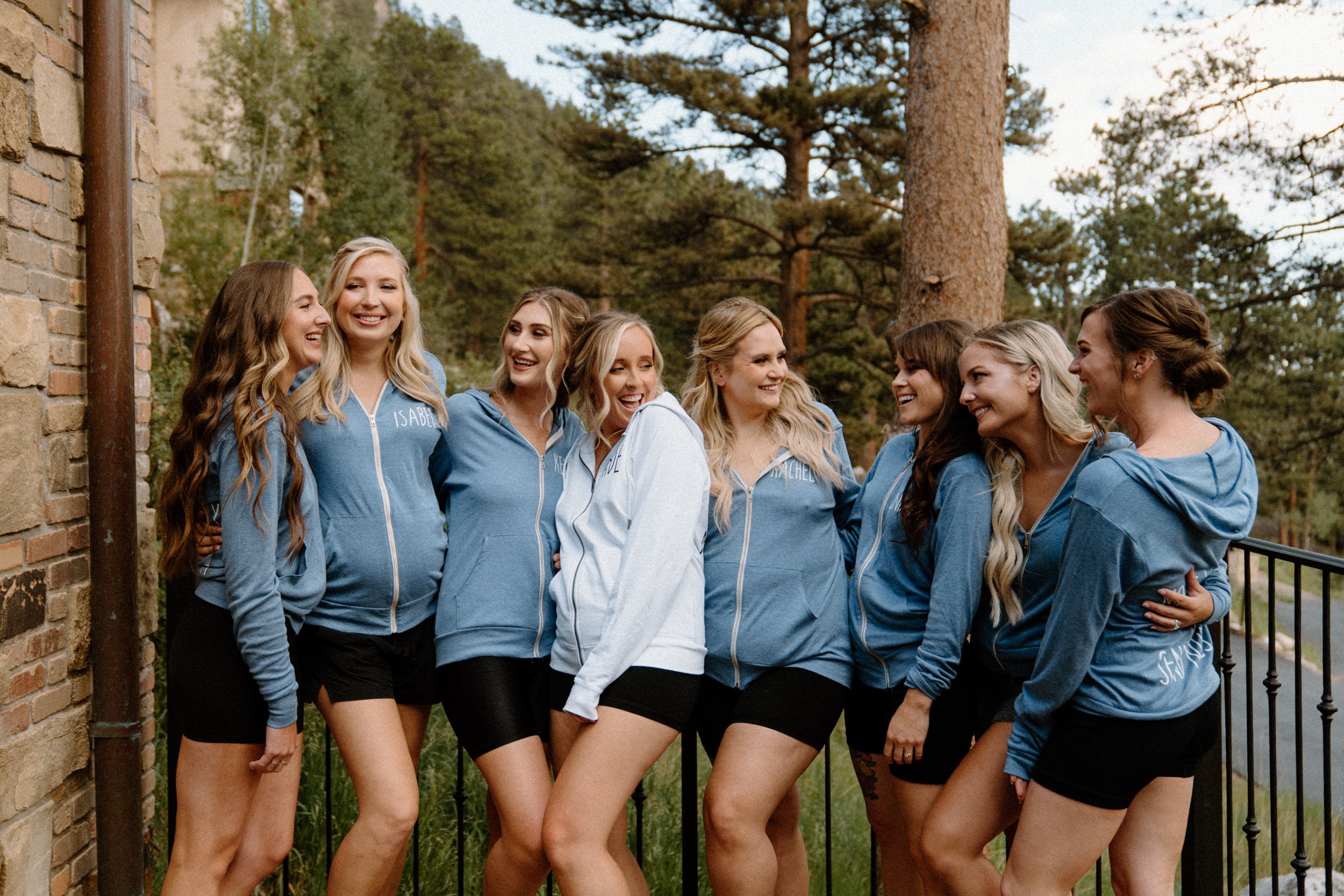 The bride poses with her bridesmaids in matching blue jackets