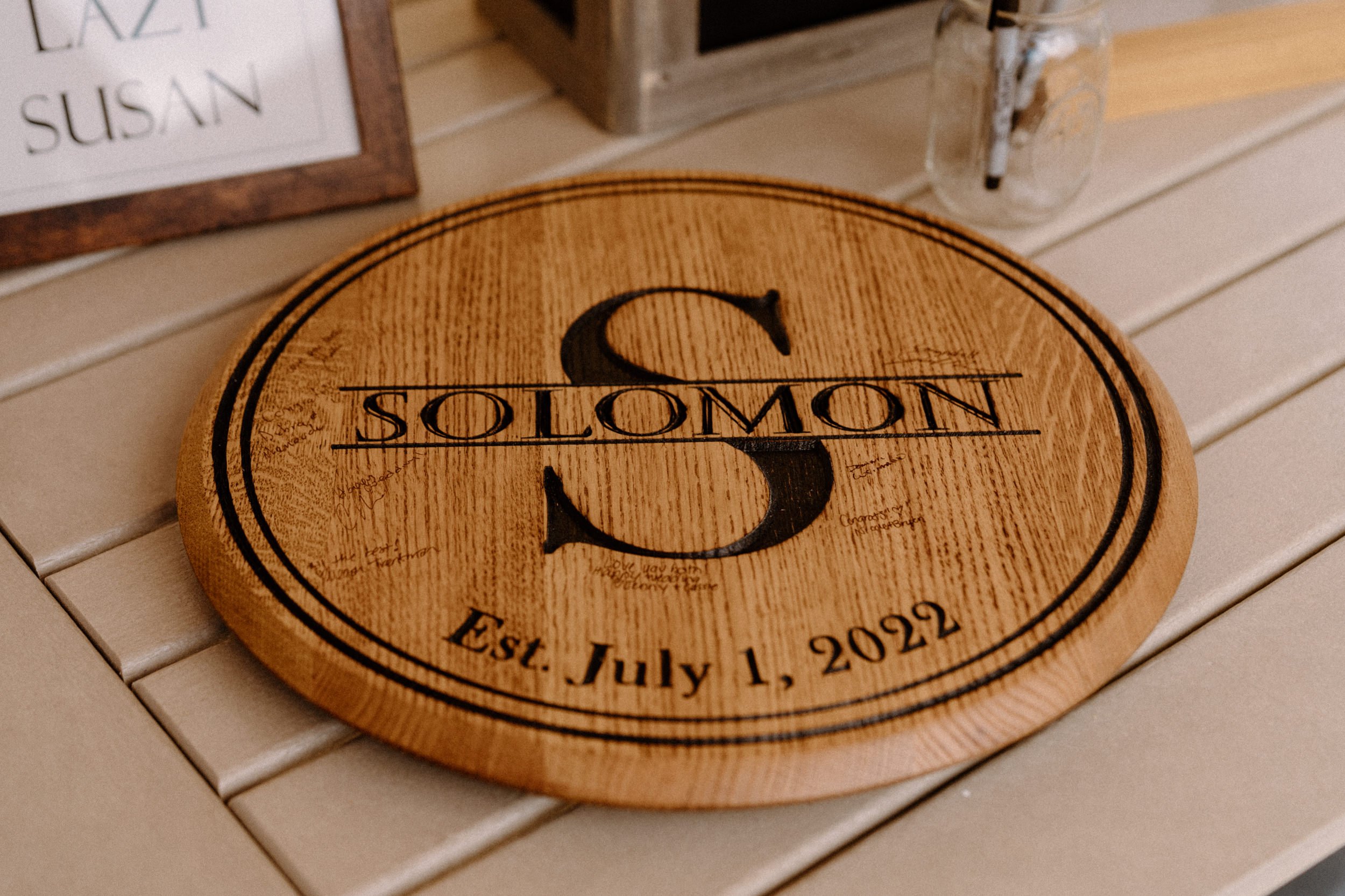 A round wooden sign with a large S and "Solomon" that guests write notes on