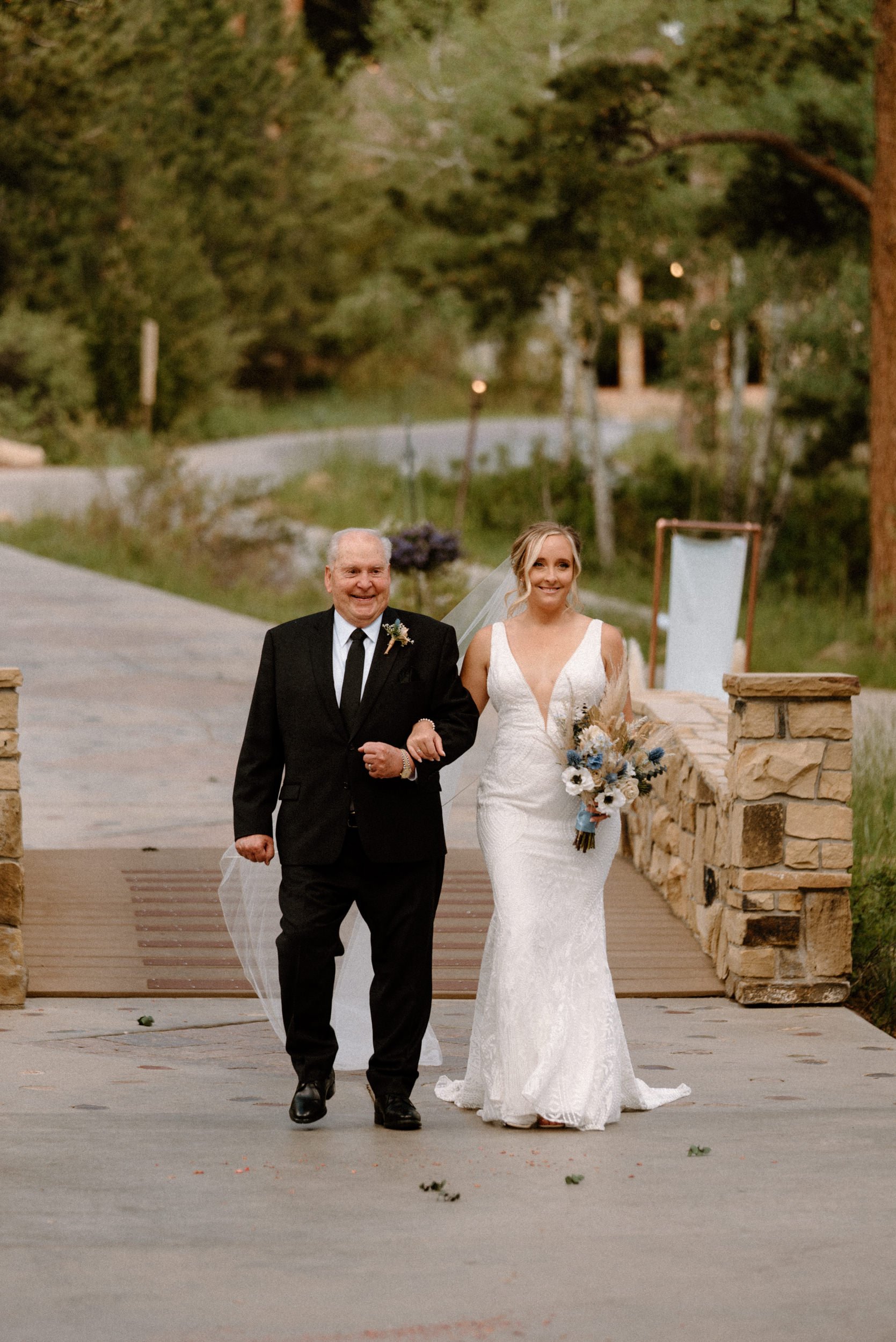 The bride and her father walk down the aisle together at Della Terra Mountain Chateau in Estes Park, CO