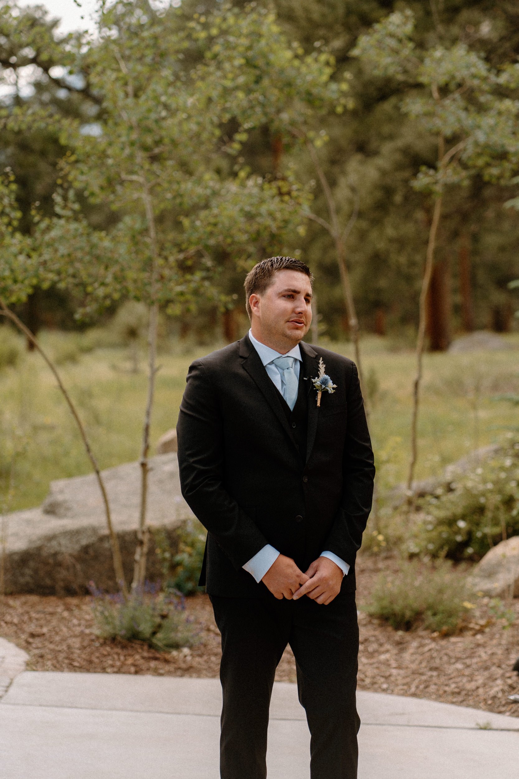 The groom emotionally watches the bride walk down the aisle toward him