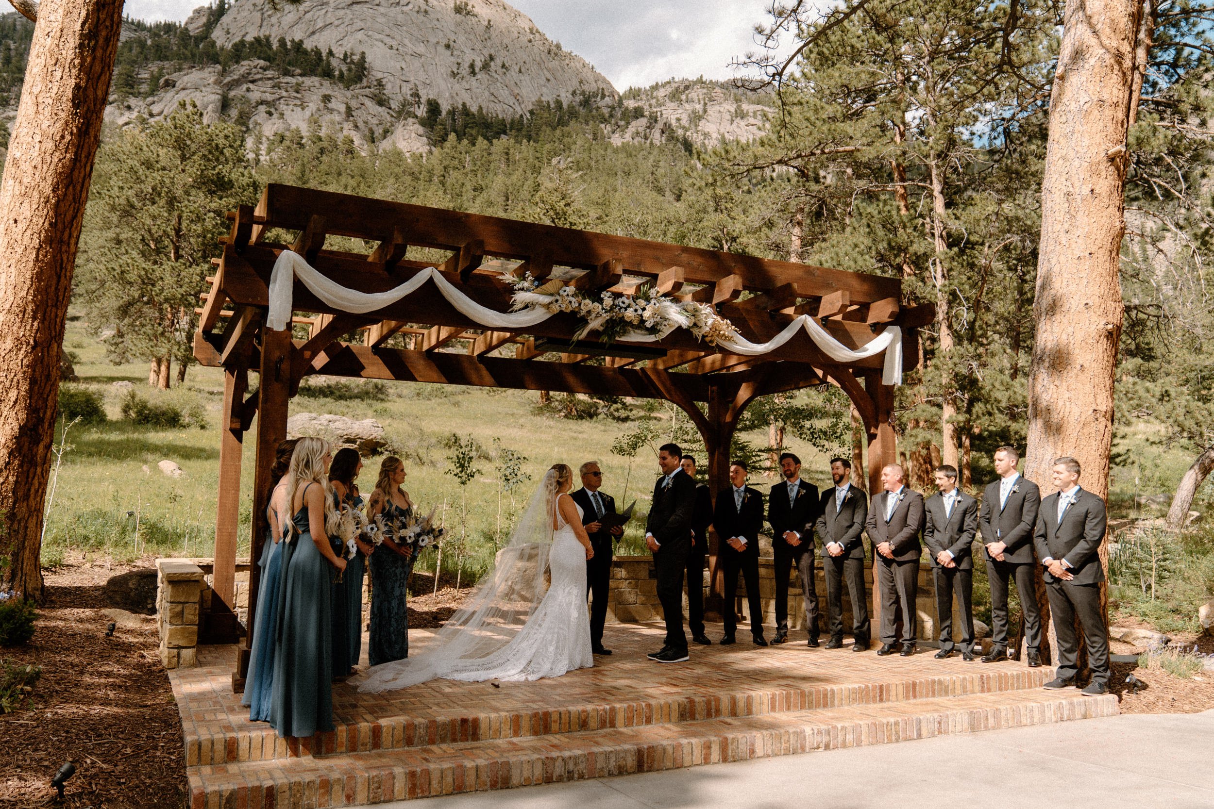 The bride and groom and wedding parties stand at the altar together at the Della Terra Mountain Chateau in Estes Park, CO