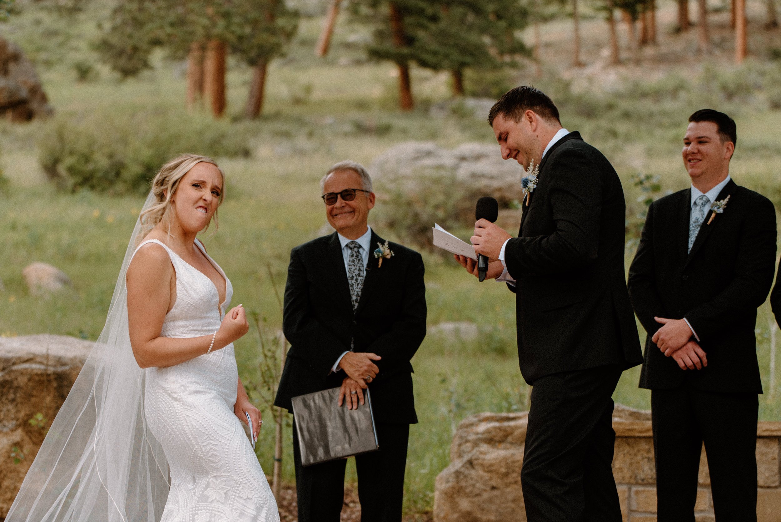 The bride makes a fist bump as the groom reads his vows to her