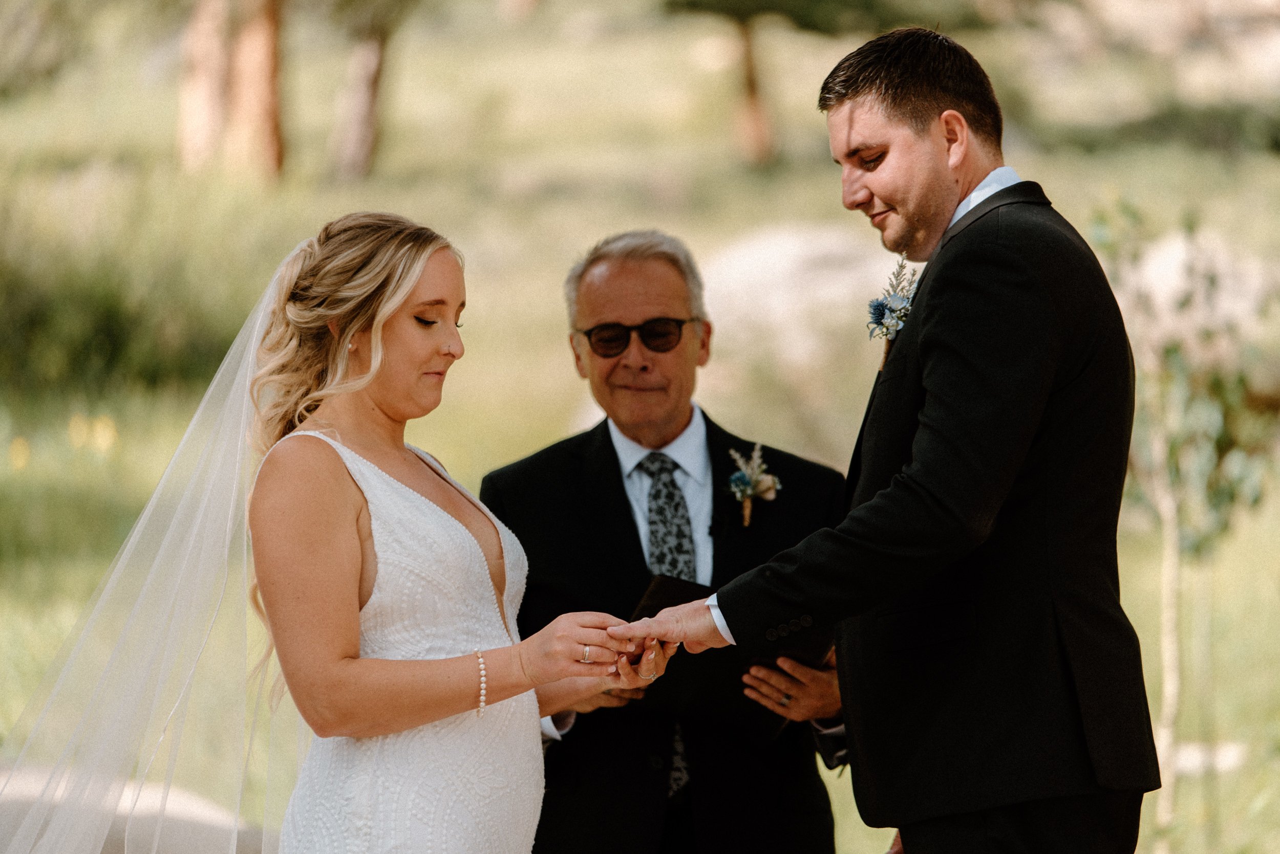 The bride places the wedding band on the groom's finger