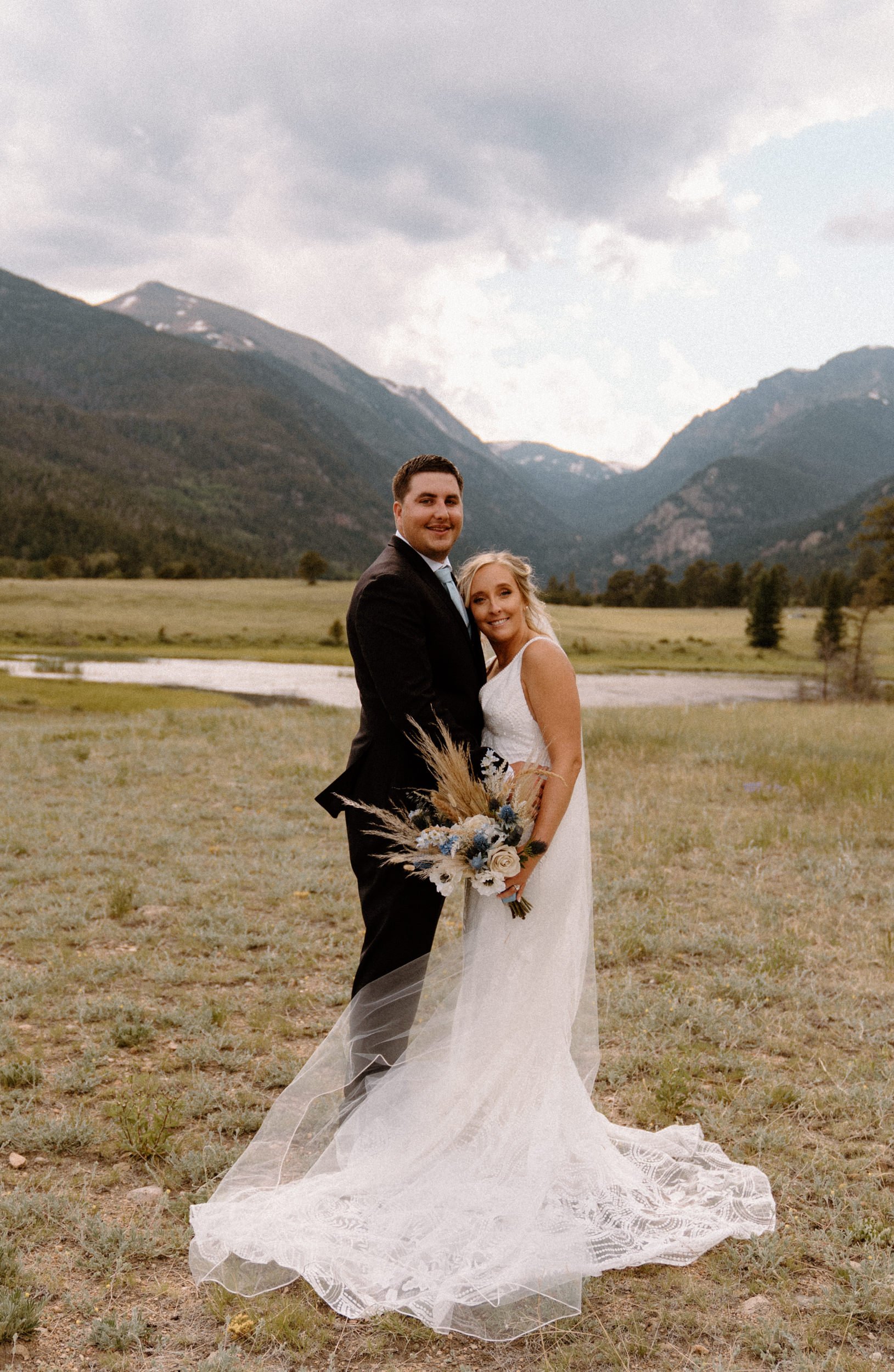 The bride and groom pose in front of the mountains in Estes Park, CO