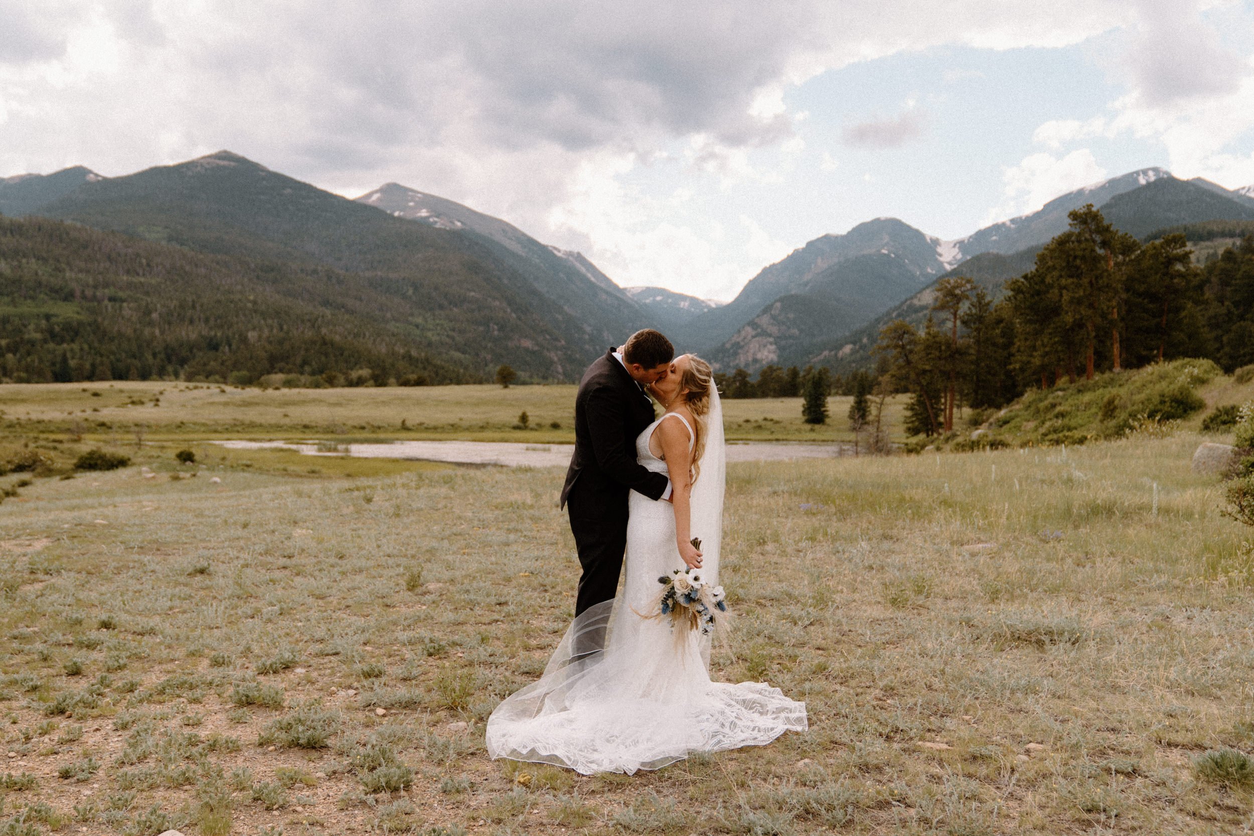 The bride and groom kiss in a mountain meadow in Estes Park, CO