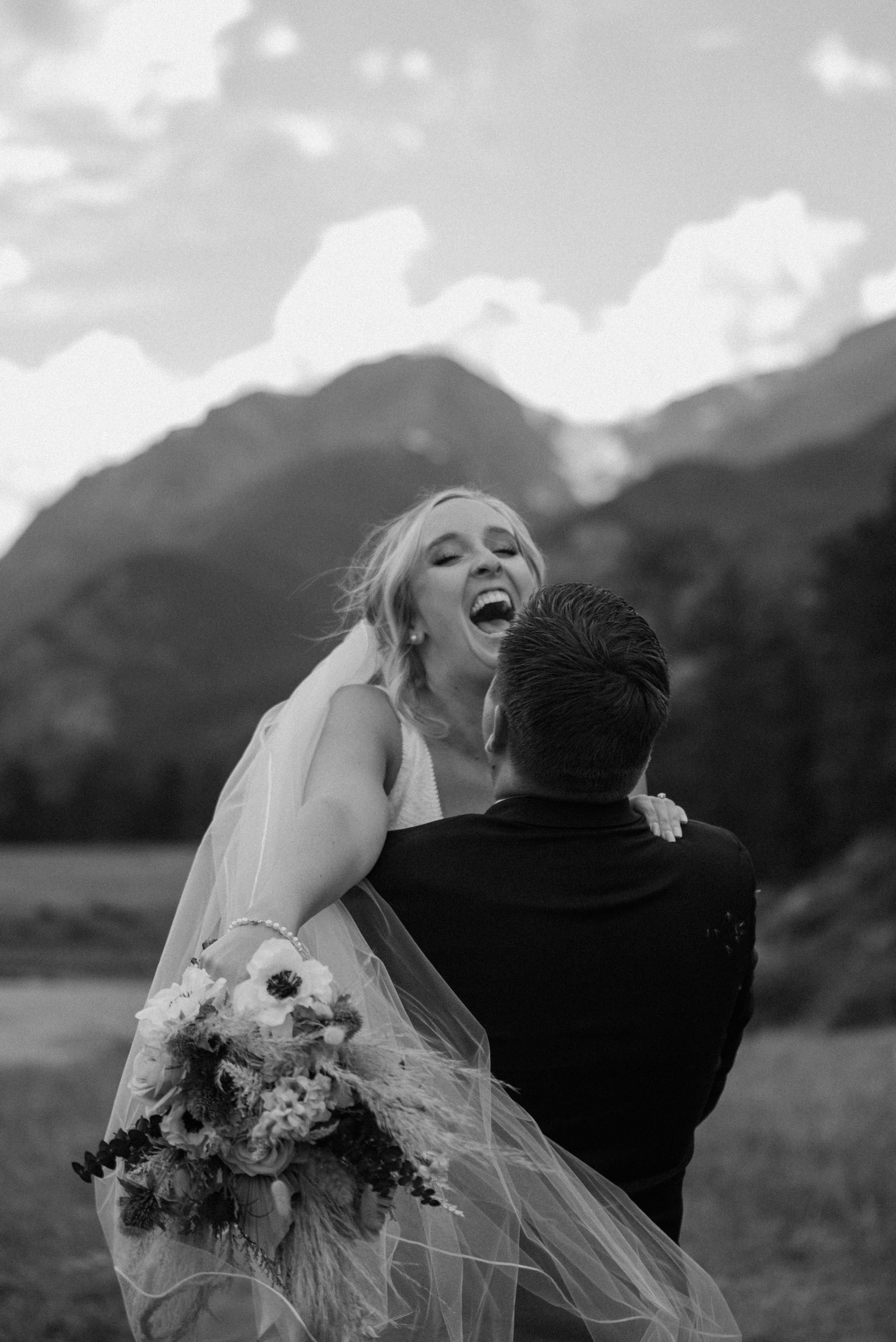 The bride laughs as the groom picks her up and twirls her