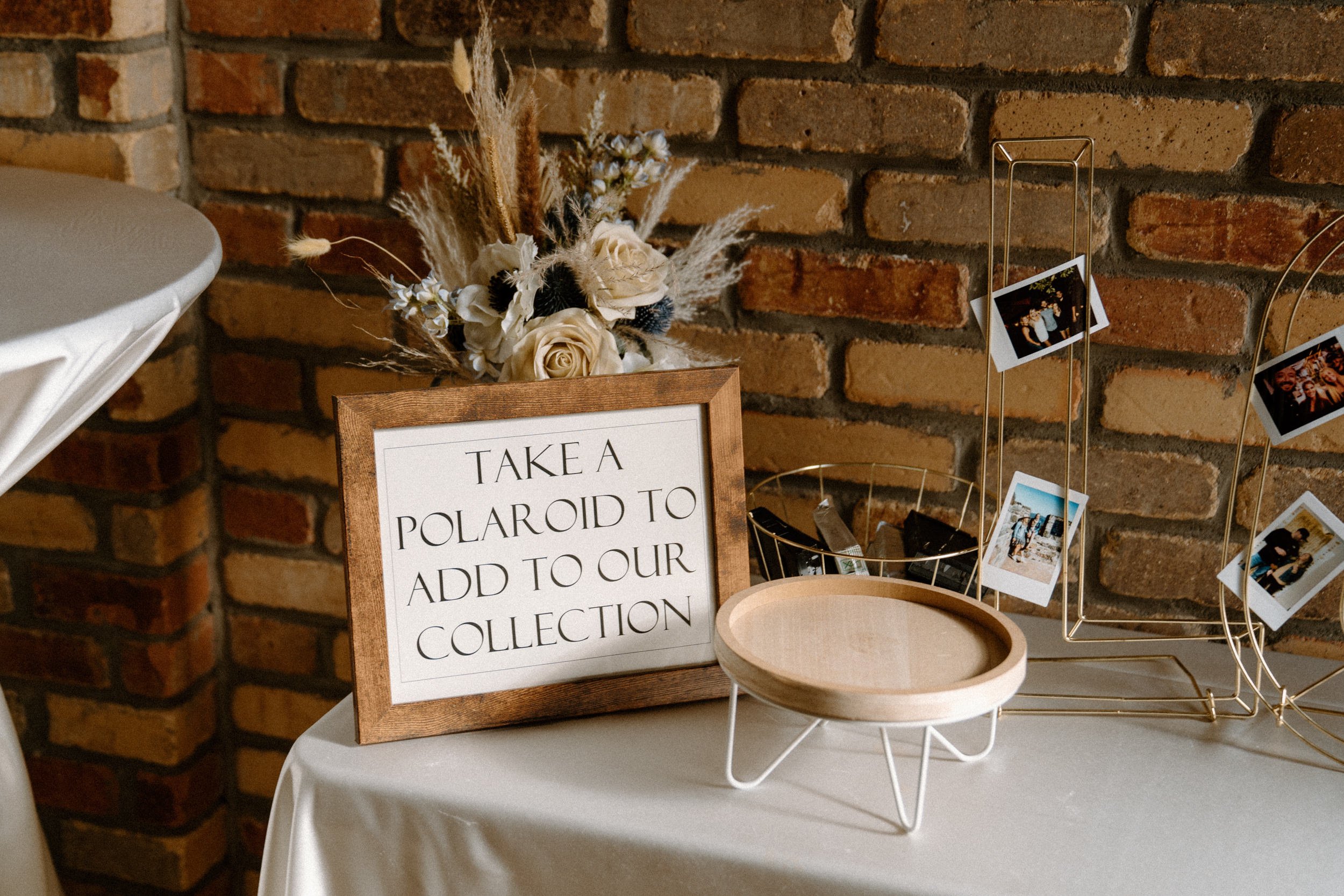 A basket of polaroid cameras and a sign that reads "Take a polaroid to add to our collection"