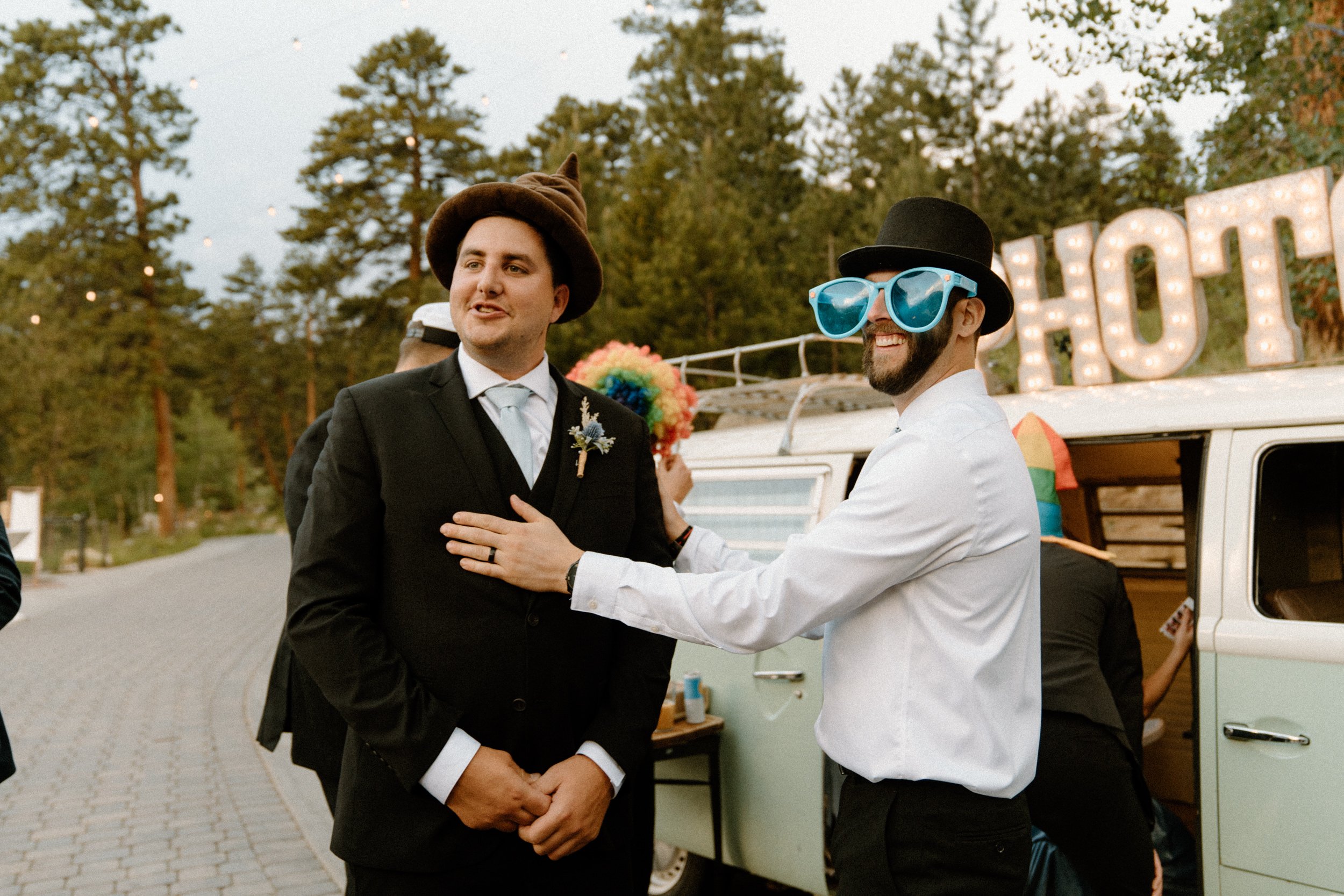 The groom and a groomsman put on funny props before the photo booth bus