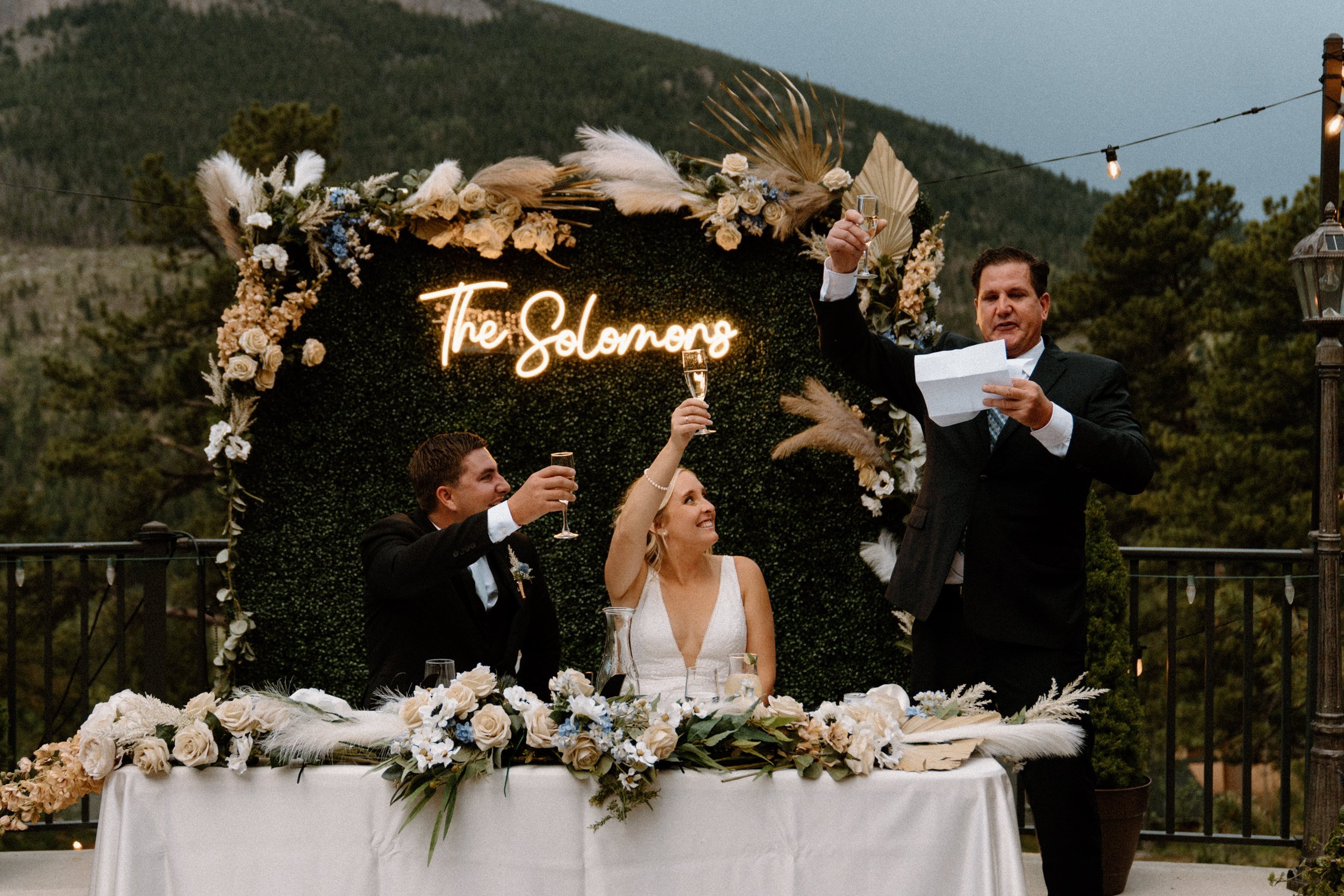 A groomsmen gives a toast to the couple as they raise their glasses