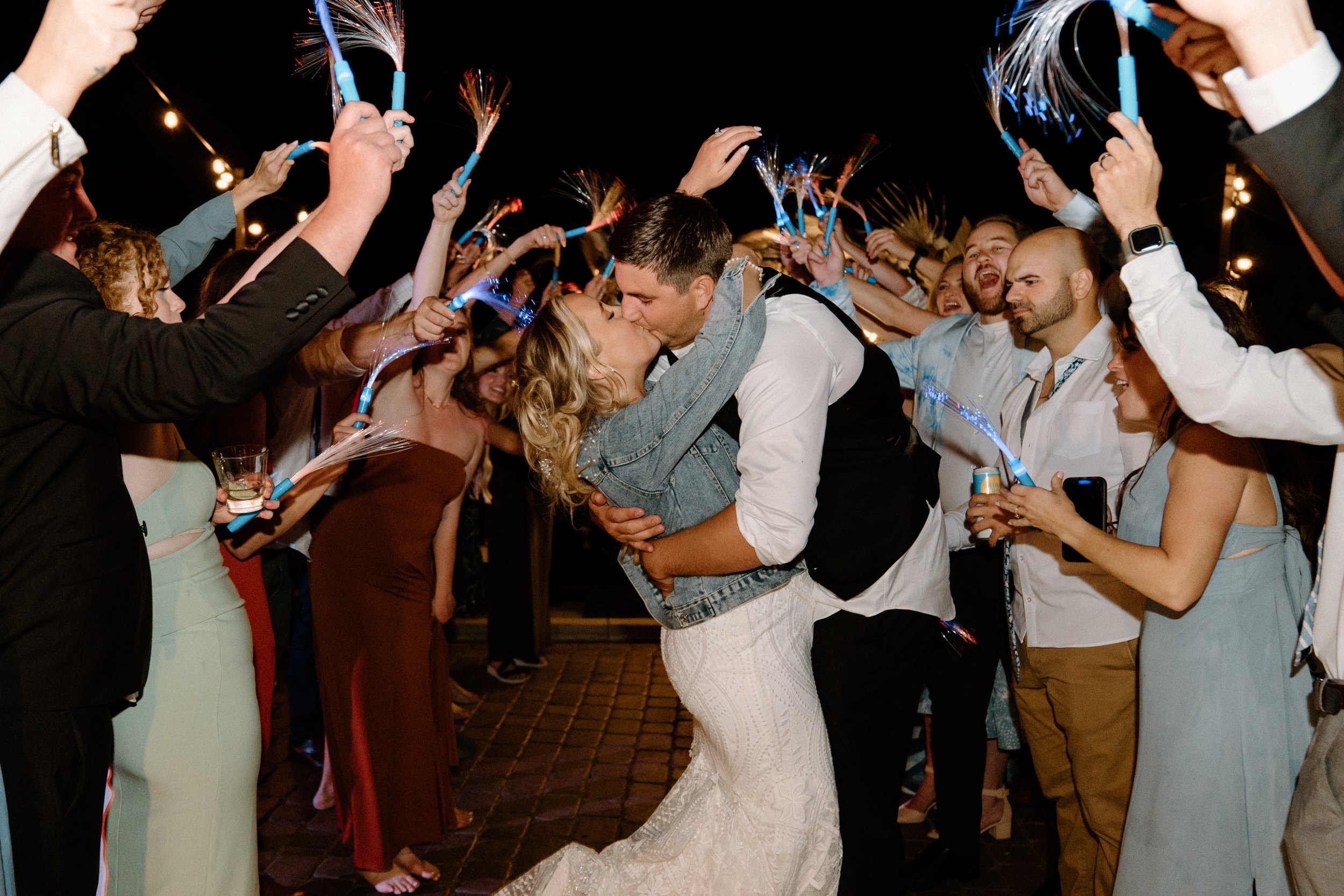 The bride and groom kiss in the glow stick tunnel as they exit