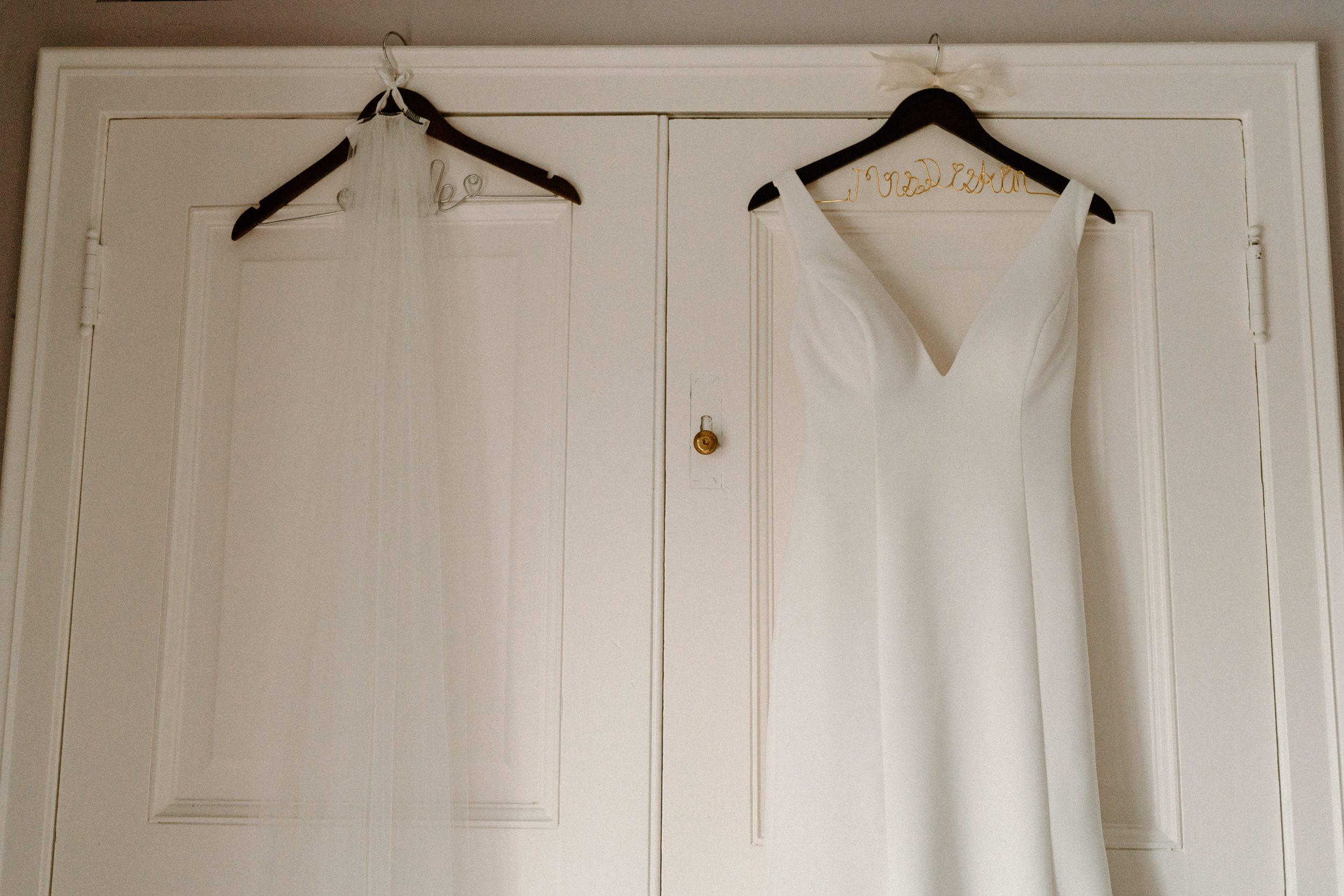 A white wedding dress and veil hang from the closet