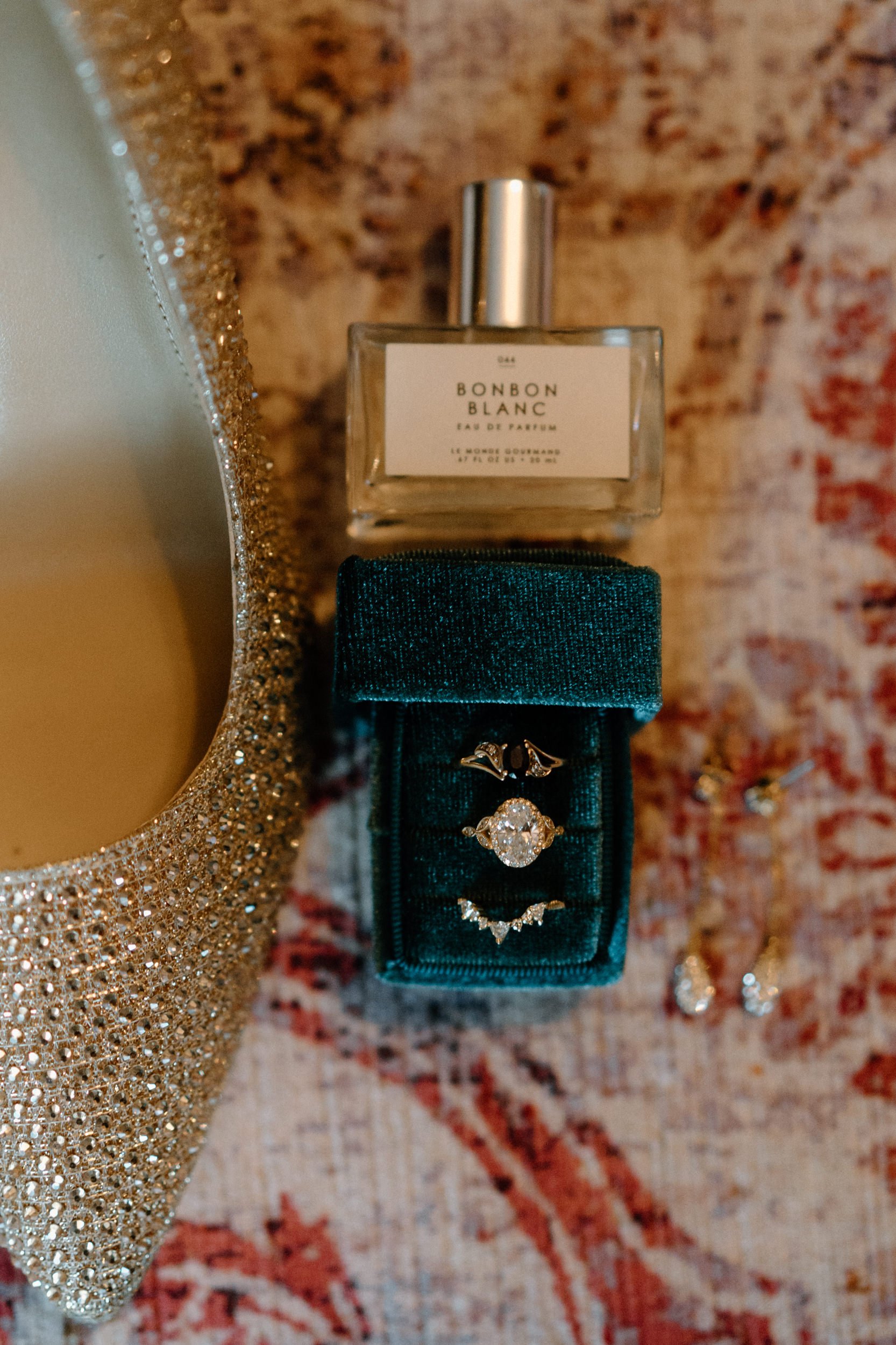 A close up of the bride's perfume, bedazzled heels, and her rings