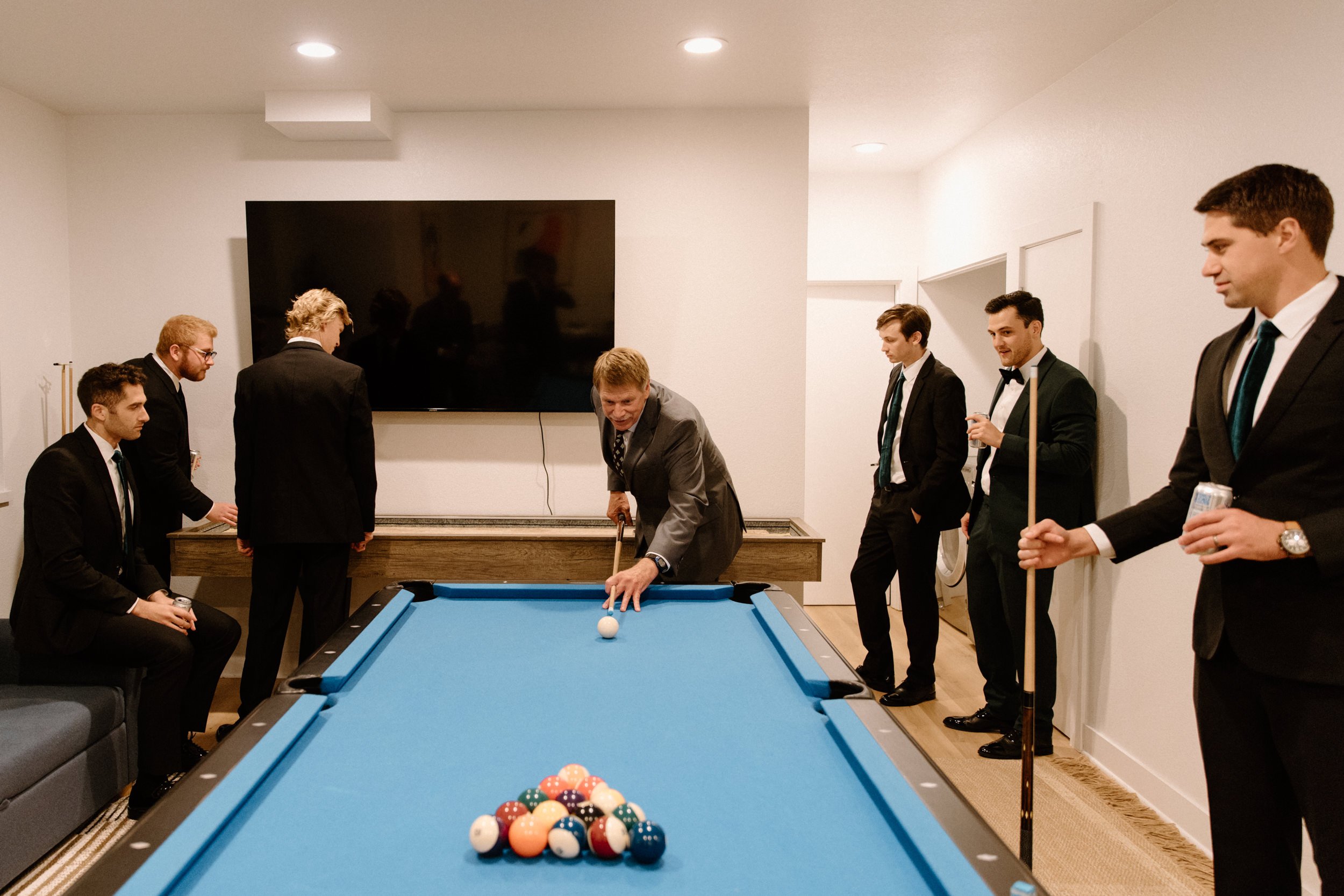 The groomsmen play a game of pool while getting ready