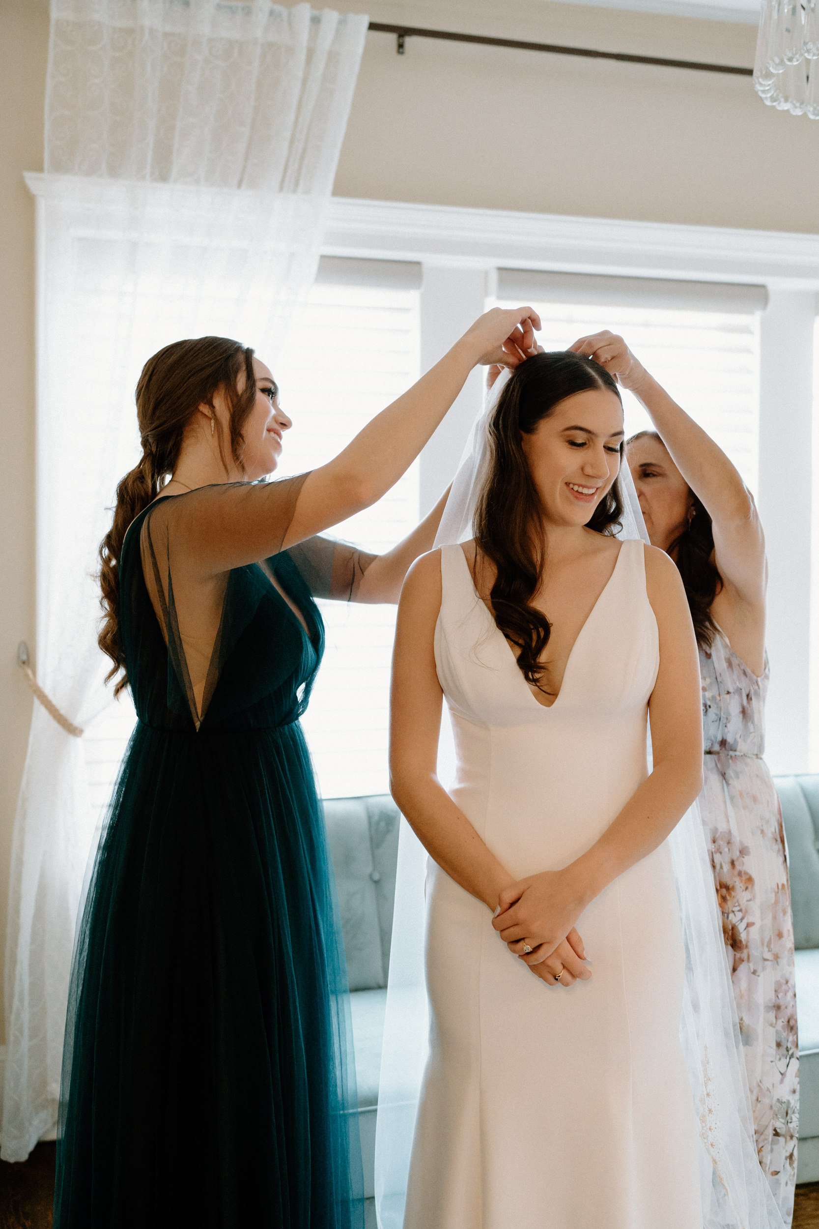 Bridesmaids help adjust the bride's veil