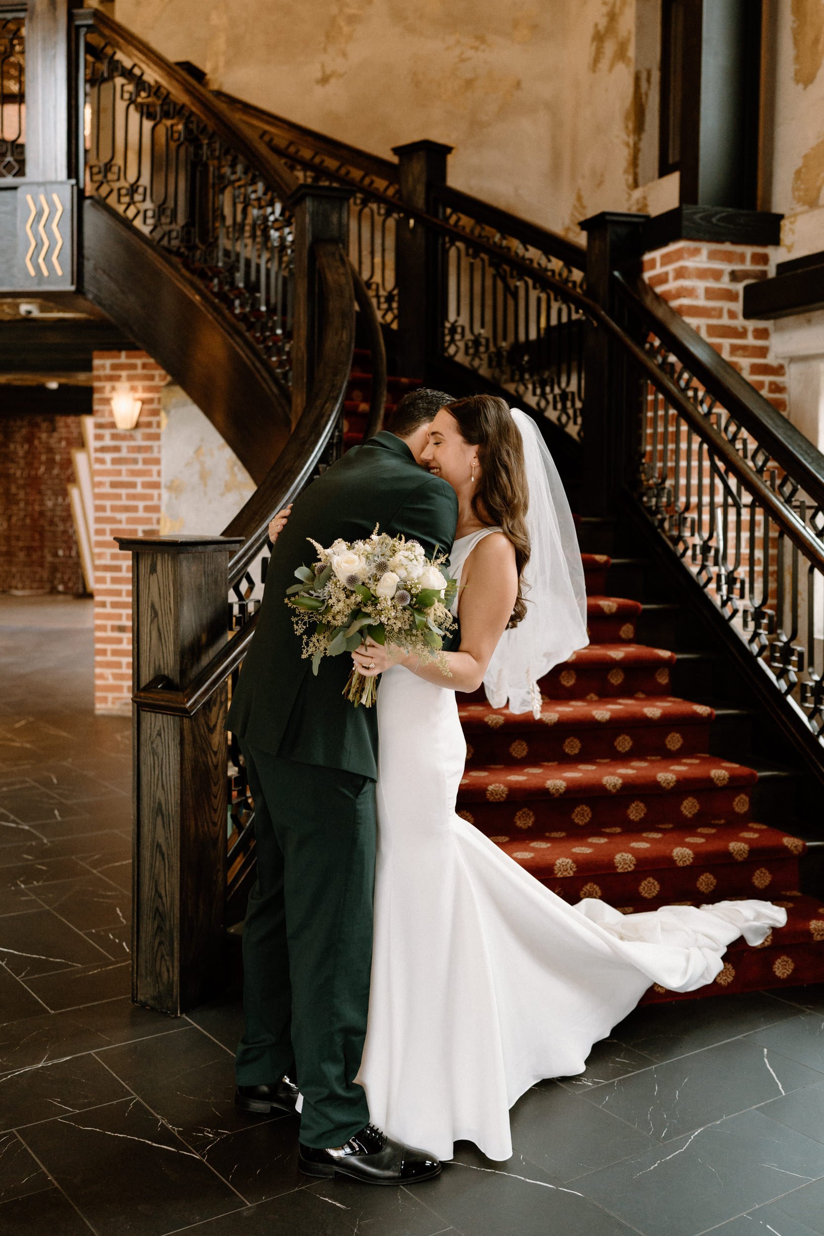 The bride and groom embrace at the bottom of the staircase at Ironworks in Denver, CO
