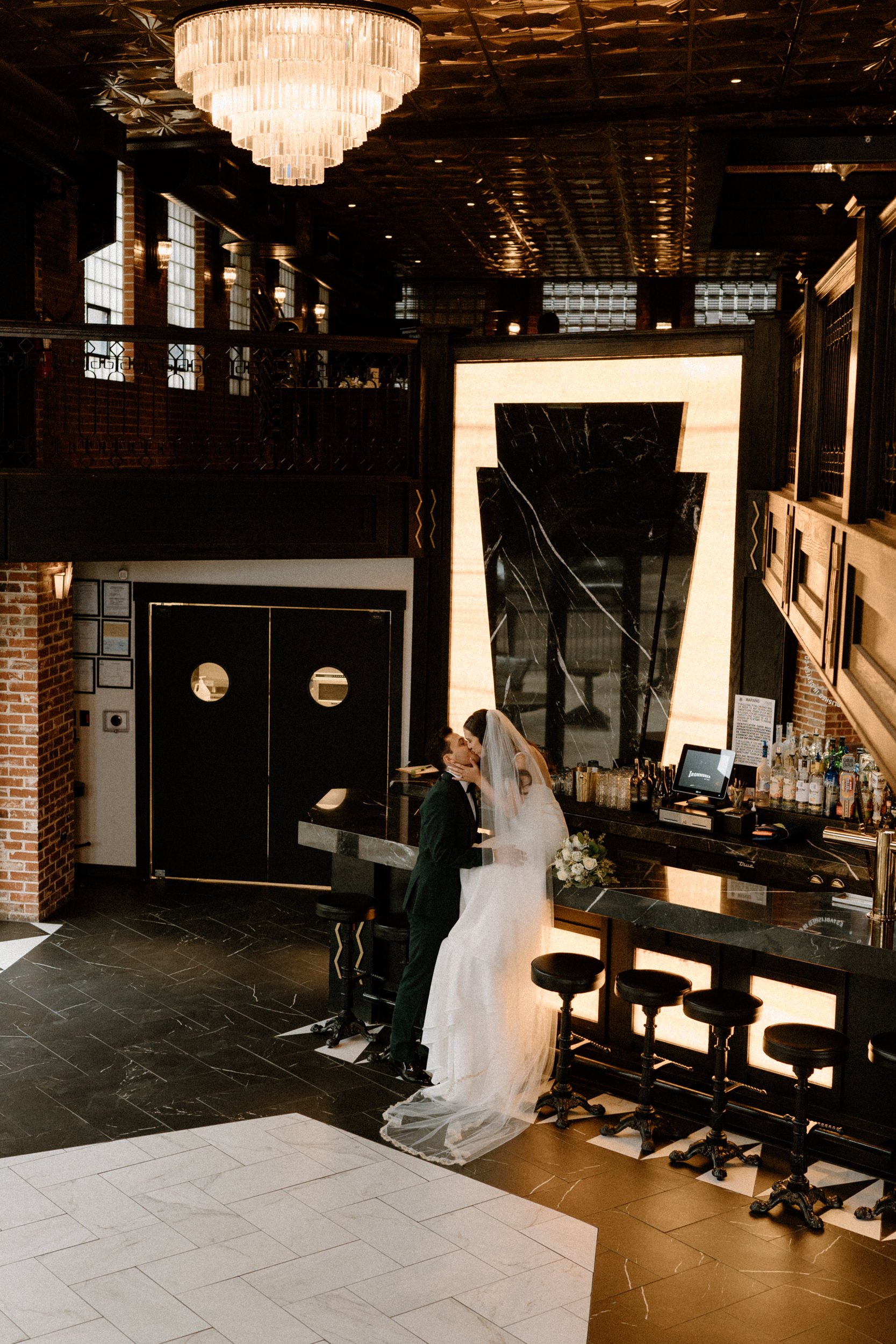 The bride and groom kiss at the bar at Ironworks in Denver, CO
