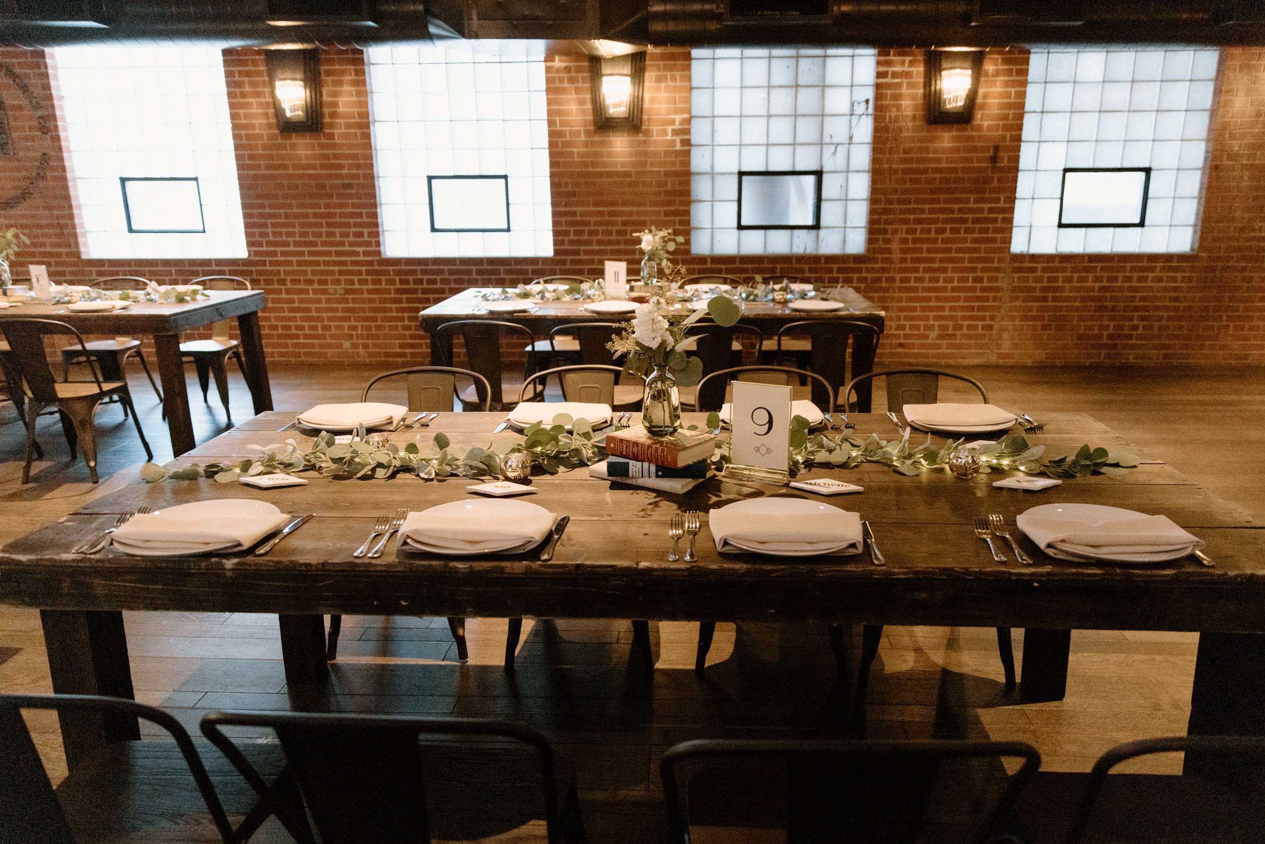 Reception tables decorated with greenery and books at Ironworks in Denver, CO