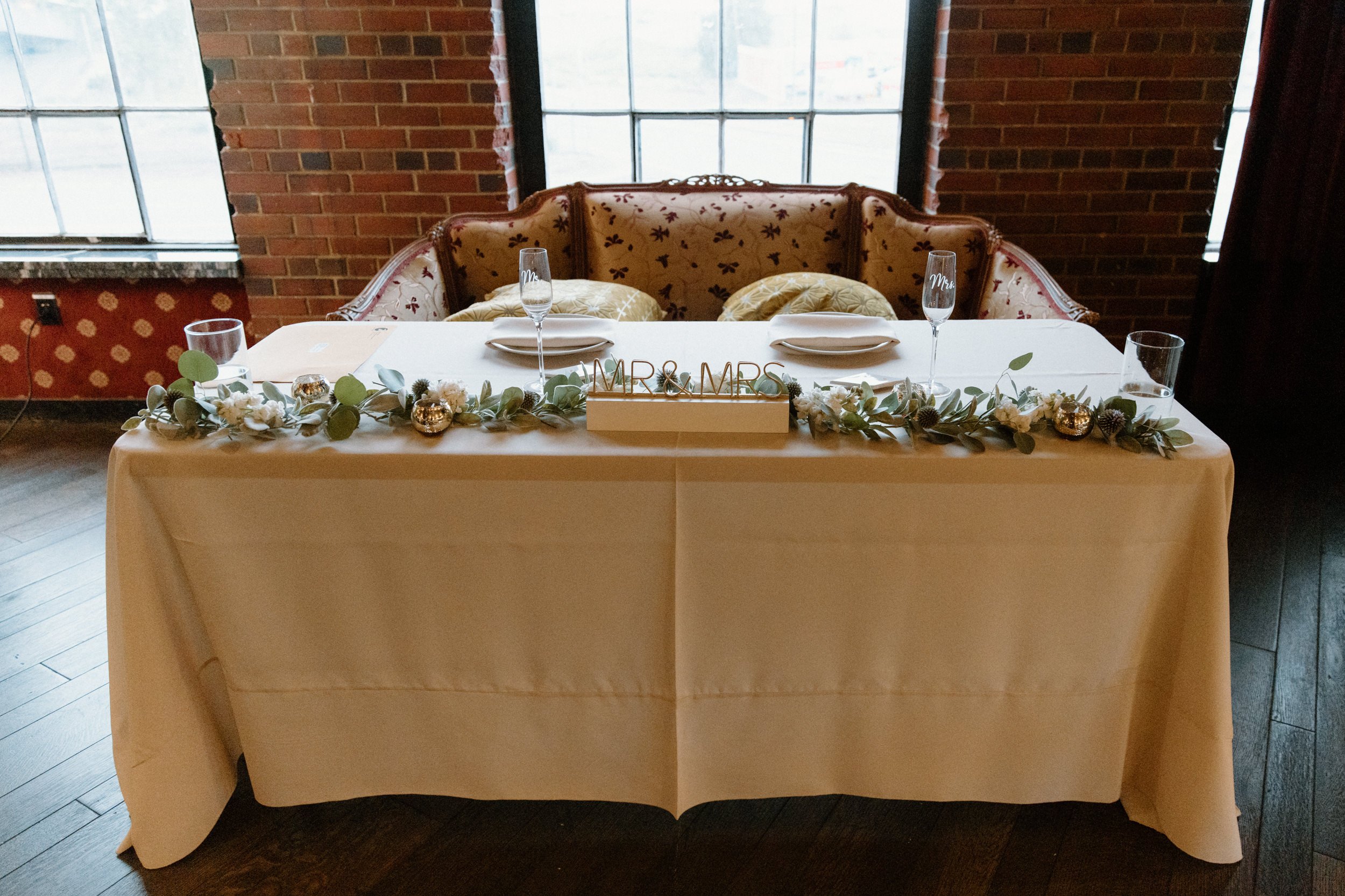 The bride and groom's reception table decorated with greenery