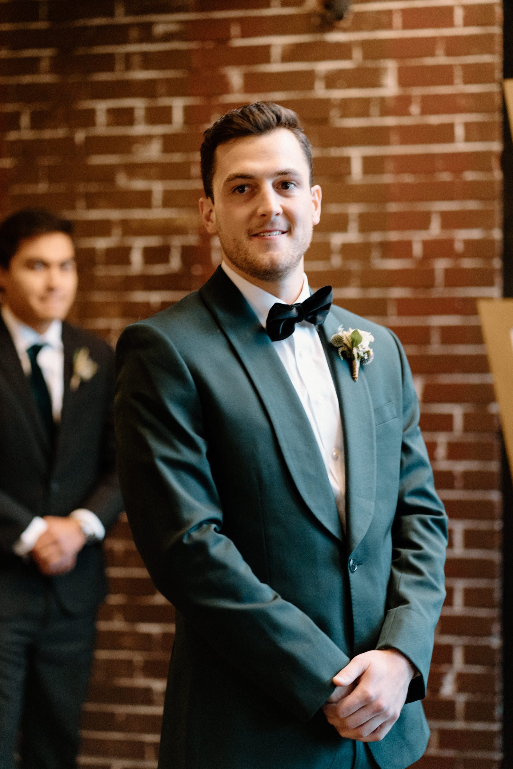 The groom smiles as he watches the bride walk down the aisle toward him
