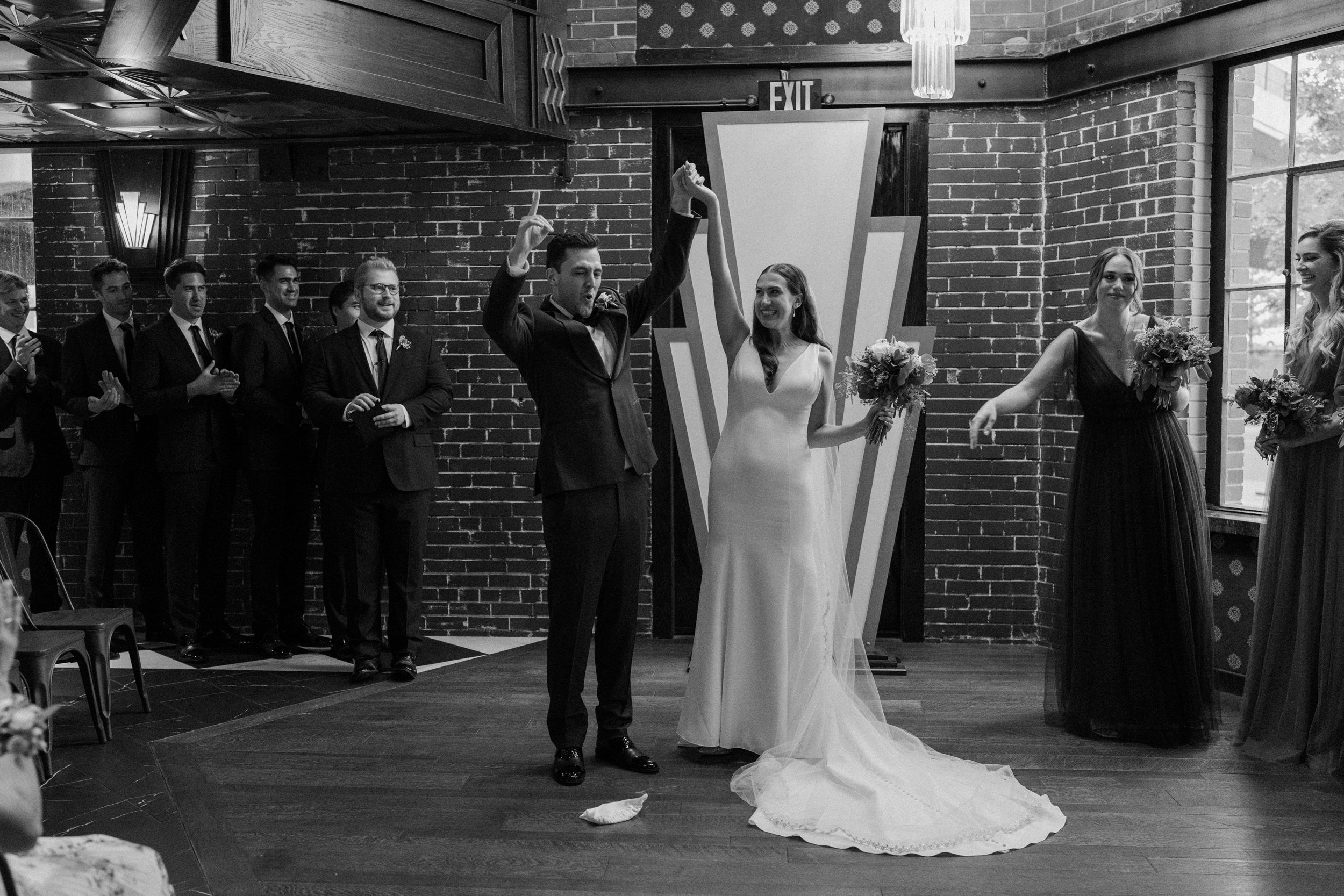 The bride and groom raise their hands in celebration at the altar