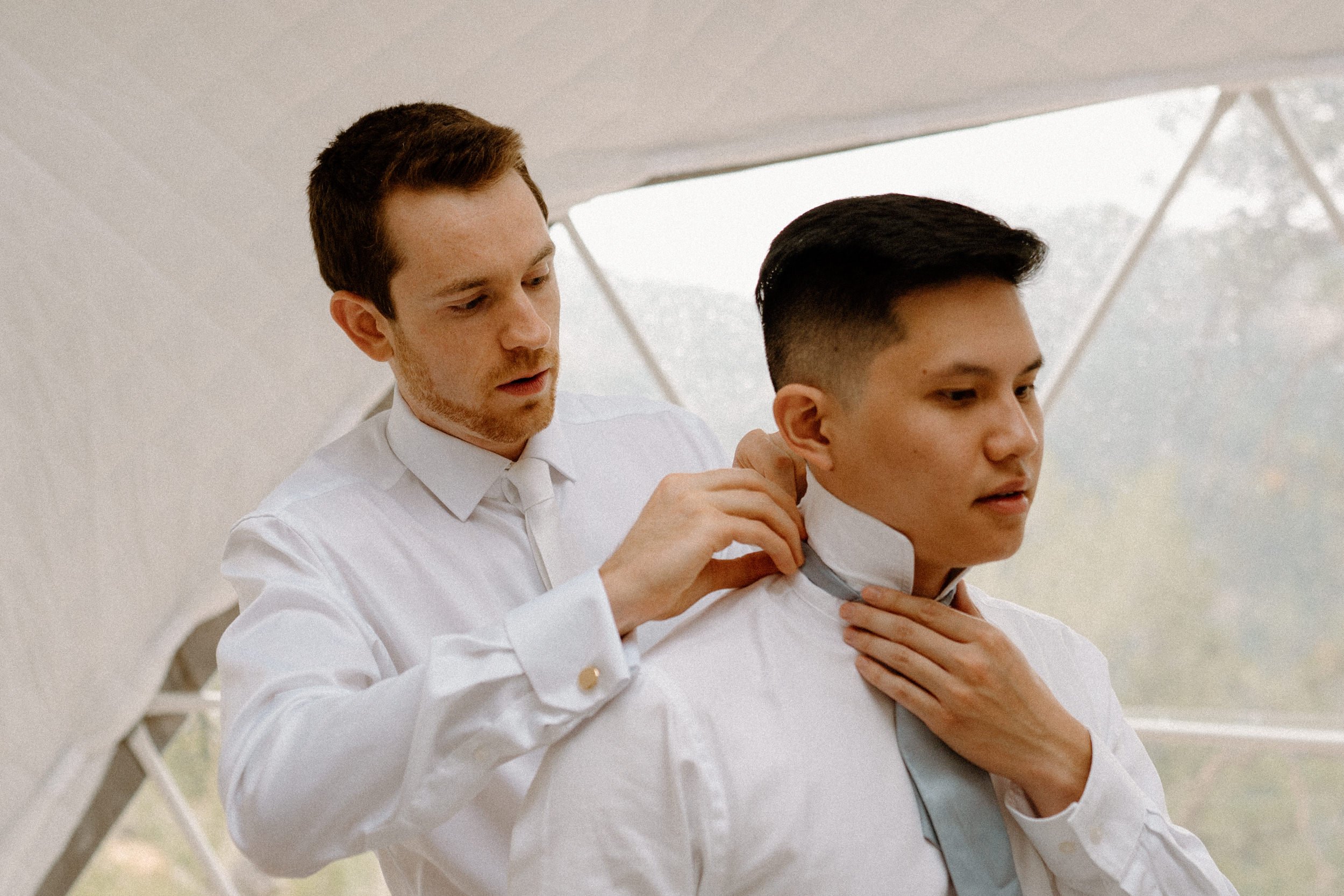 The groom helps a groomsman with his tie