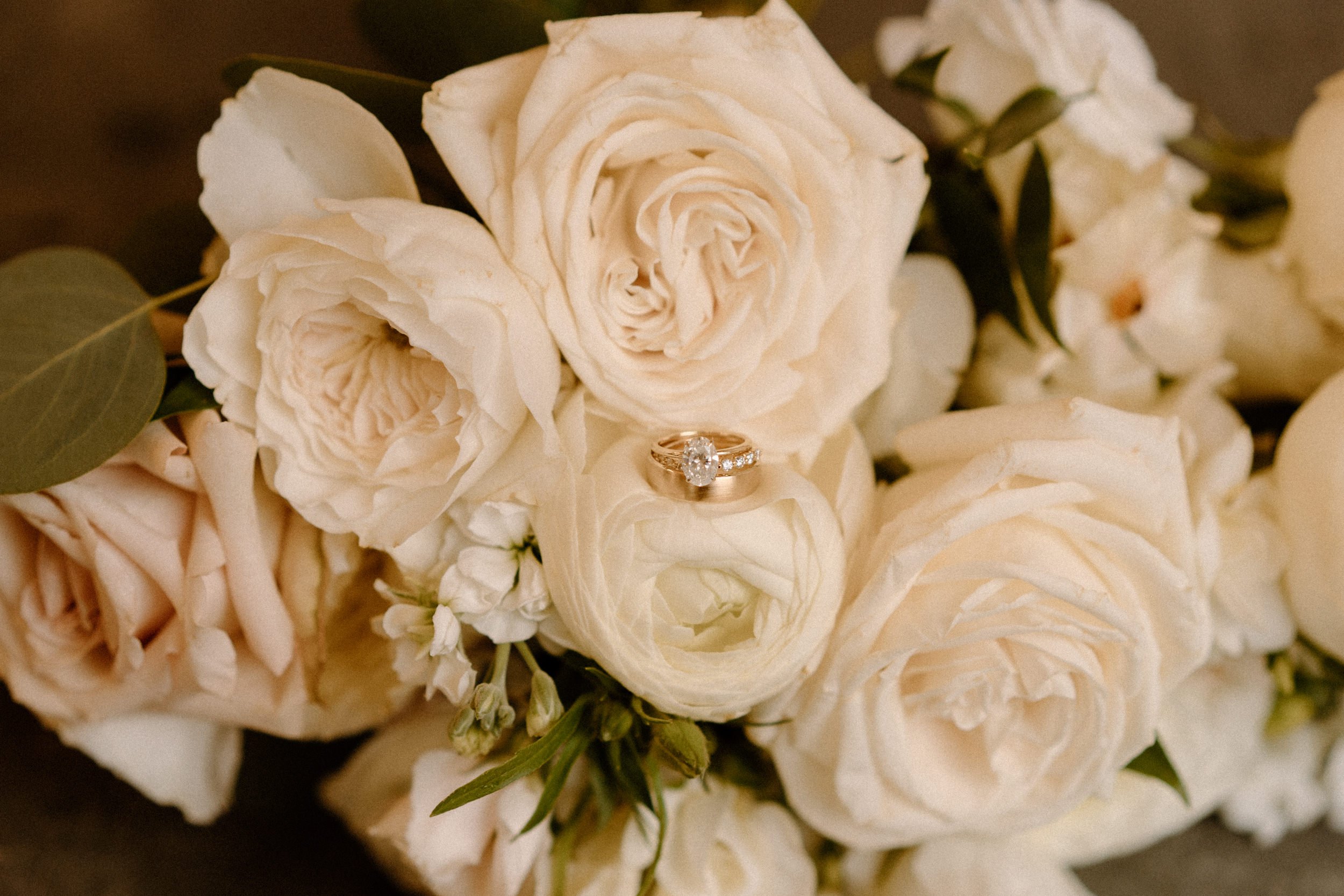 An engagement ring placed atop a white rose bouquet