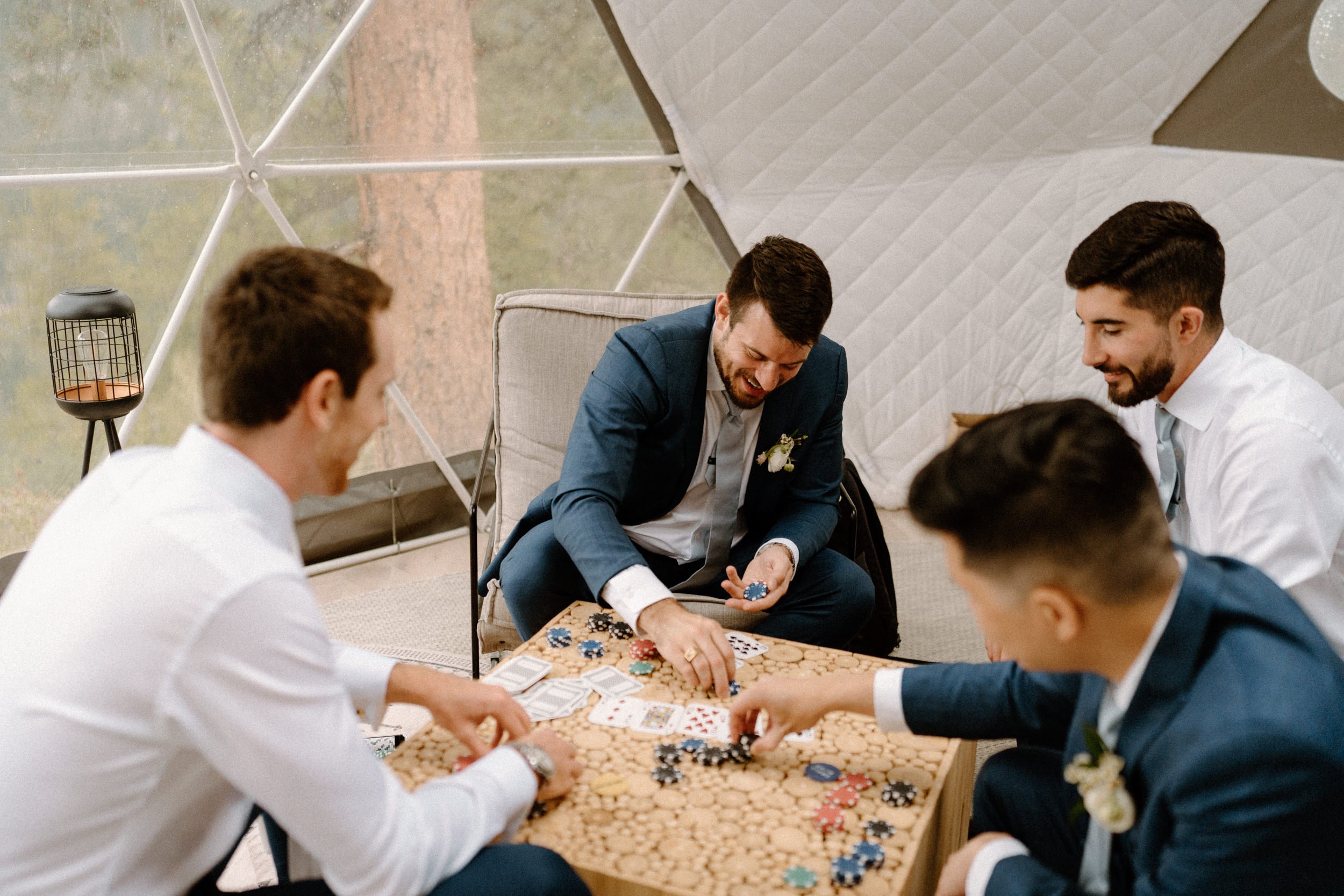 The groomsmen laugh and play cards while getting ready at North Star Gatherings in Idaho Springs, CO