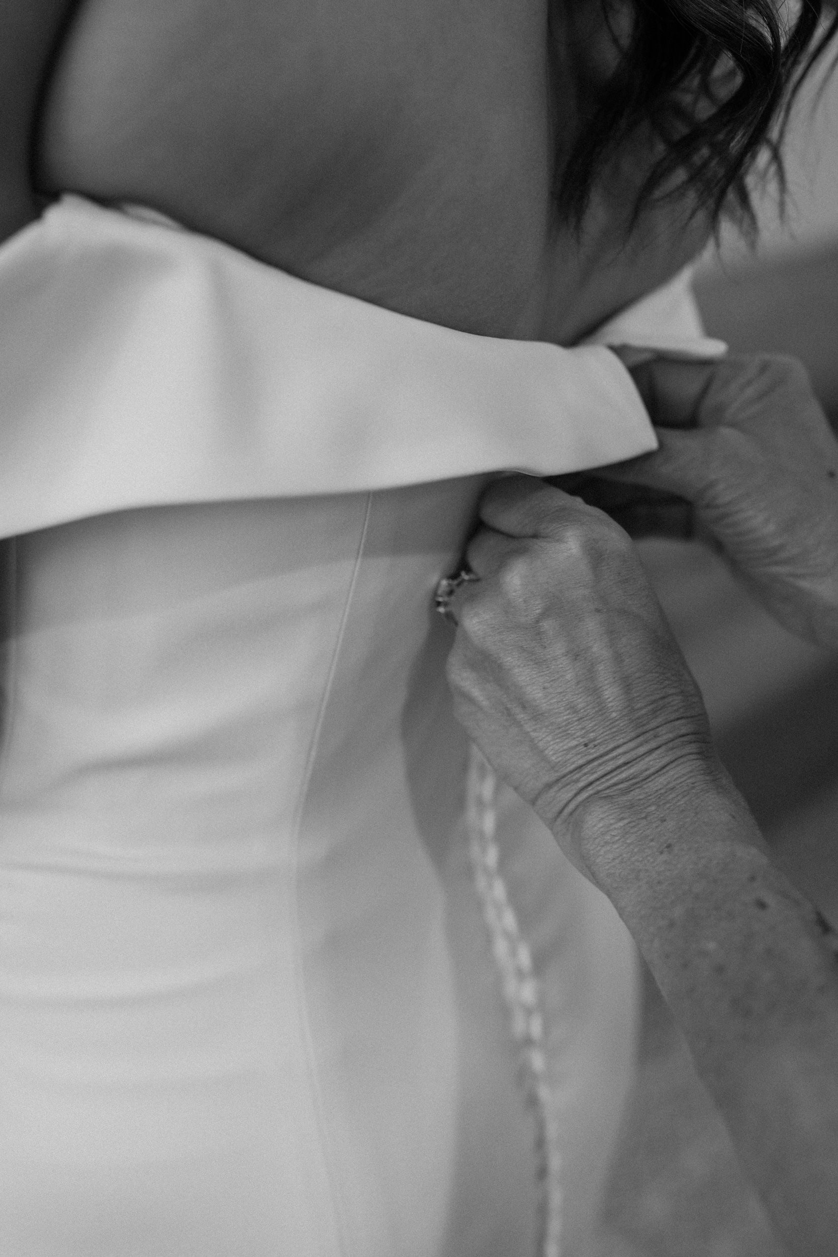 Close up of the mother of the bride button up the wedding dress