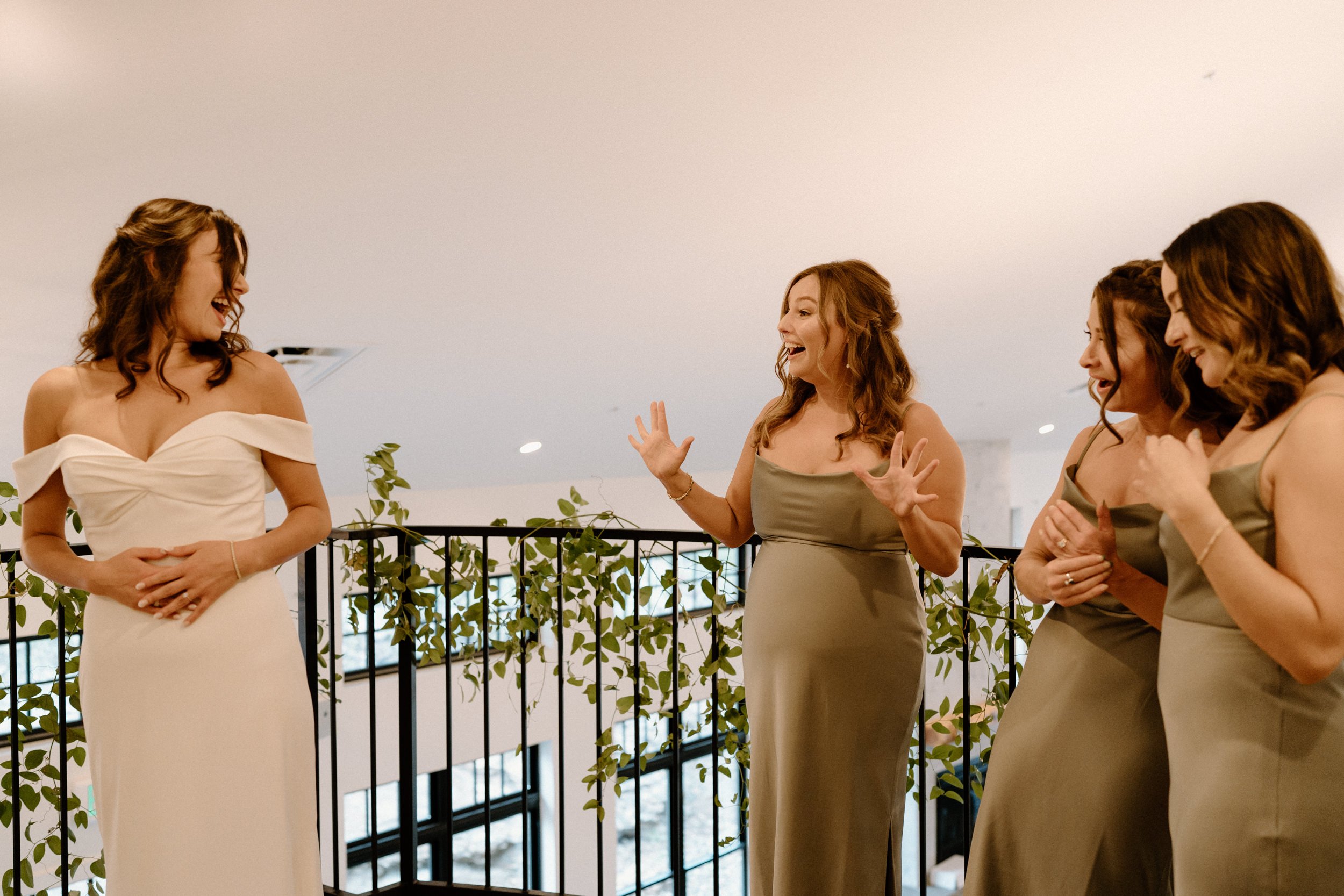 The bridesmaids smile in shock at seeing the bride for the first time in her dress
