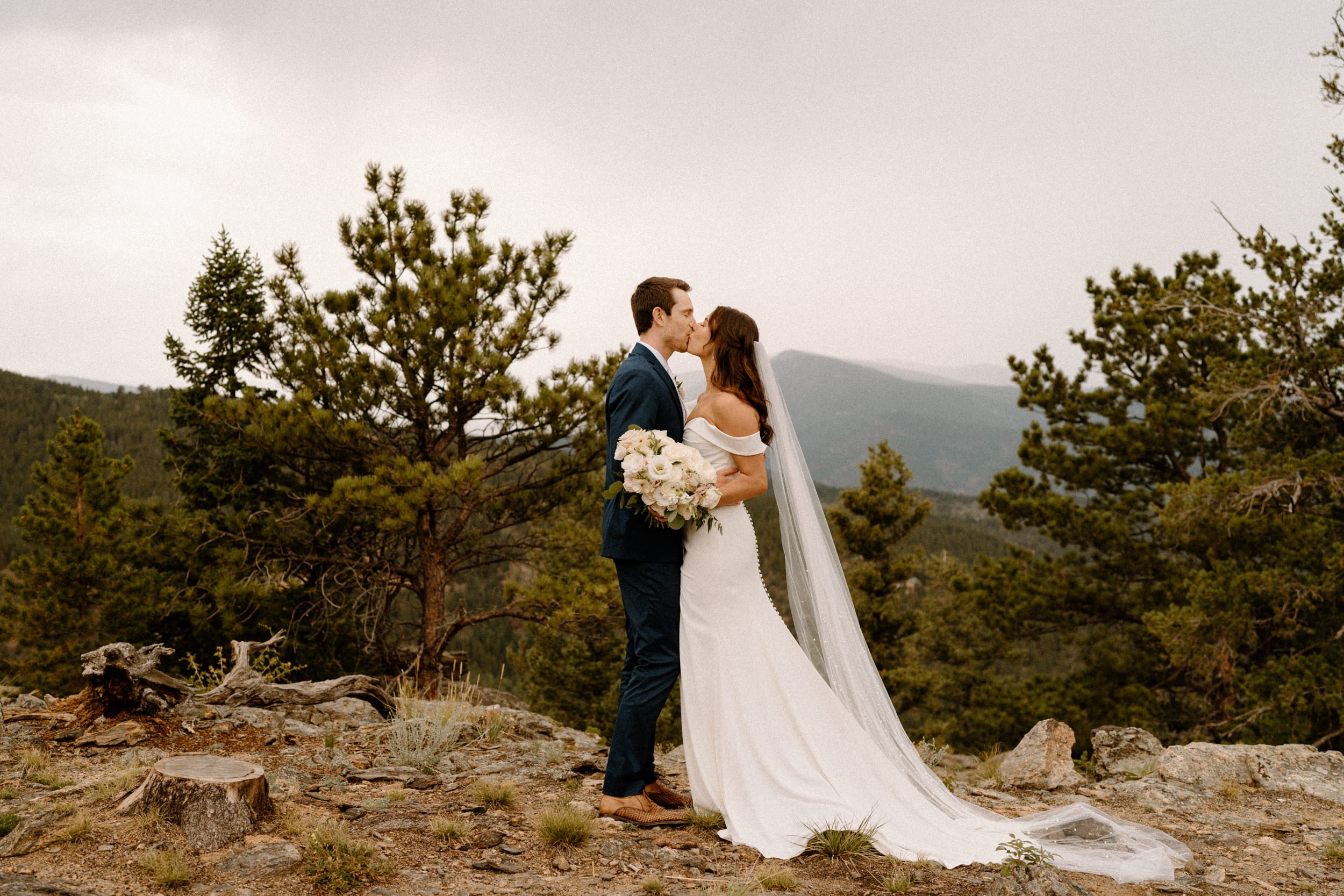 The bride and groom kiss on a mountain overlook at North Star Gatherings in Idaho Springs, CO