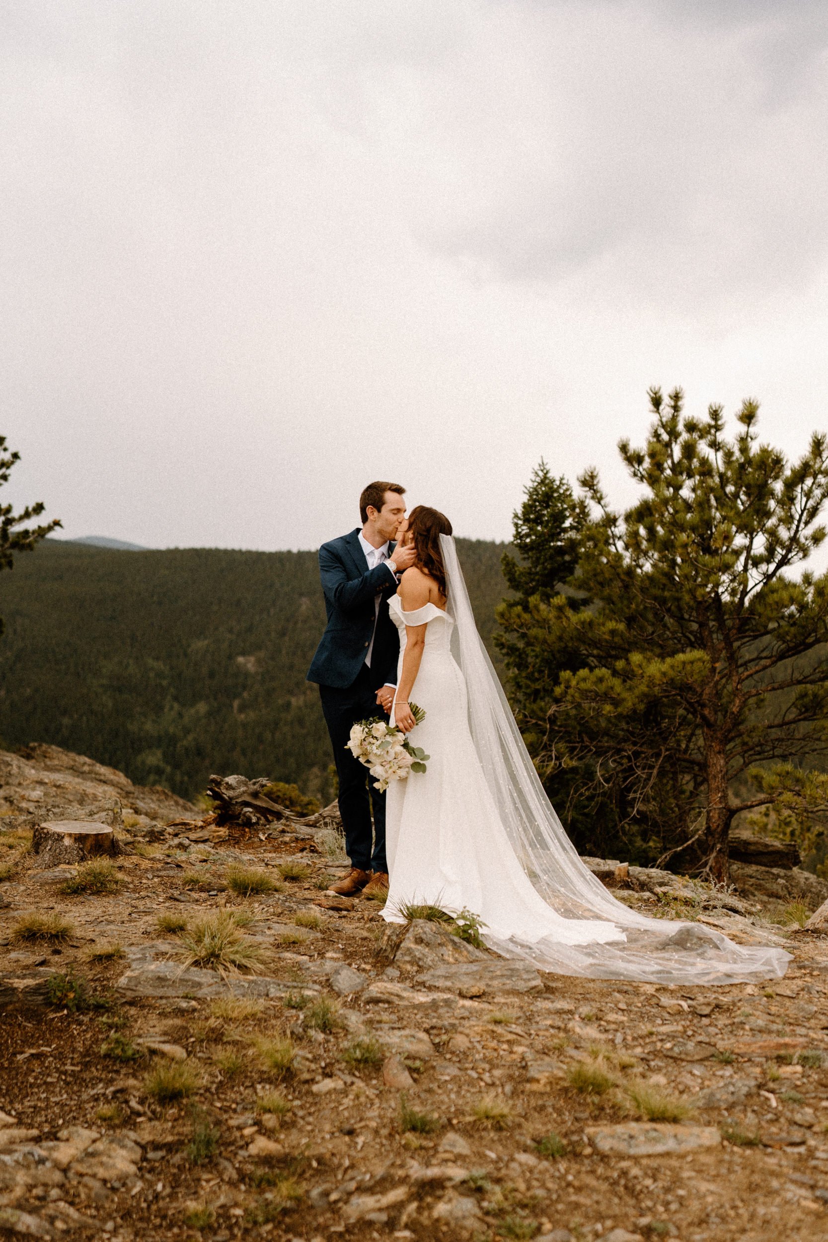 The bride and groom kiss on a mountain overlook at North Star Gatherings in Idaho Springs, CO