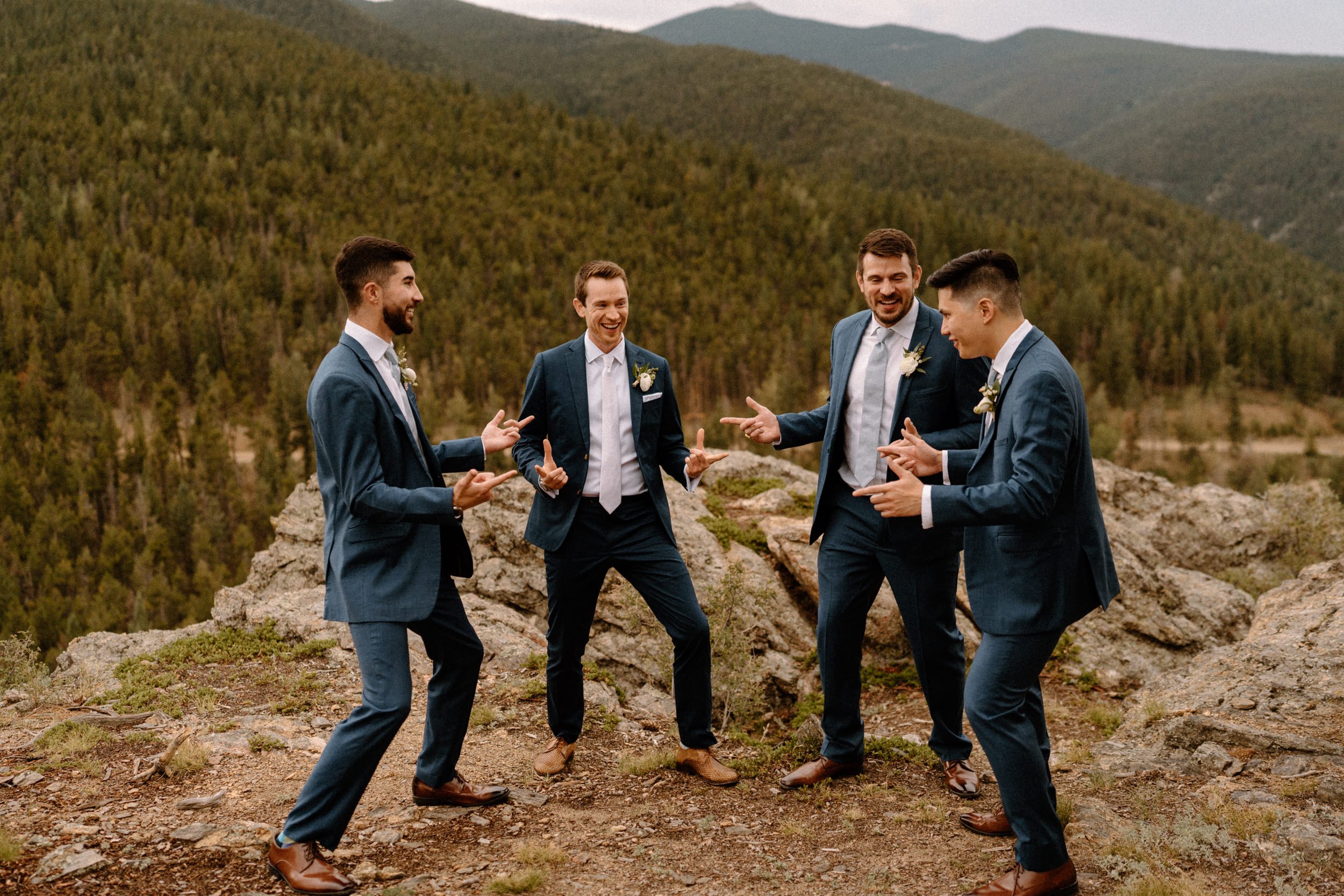 The groomsmen pose in a circle and point finger guns at each other