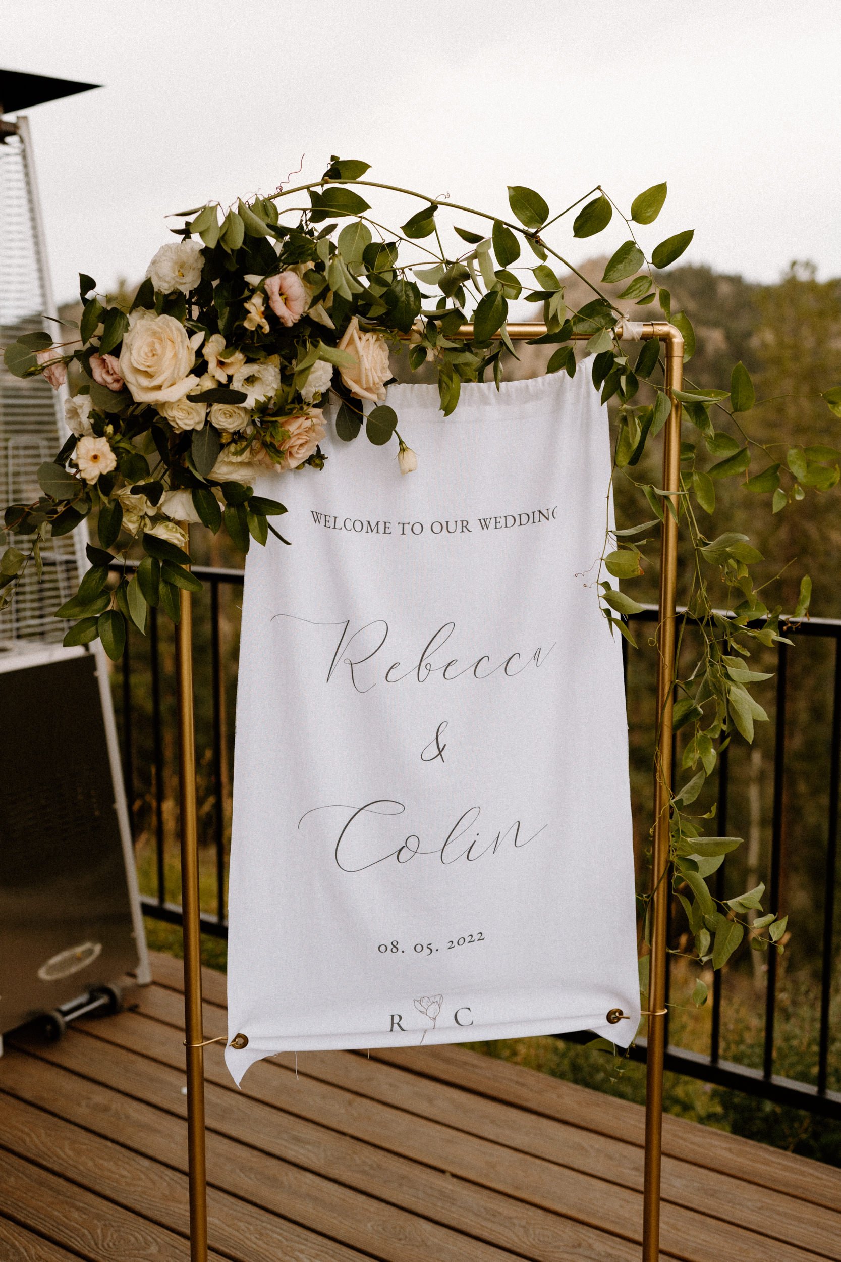 A white sign reads "Welcome to Our Wedding: Rebecca &amp; Colin"