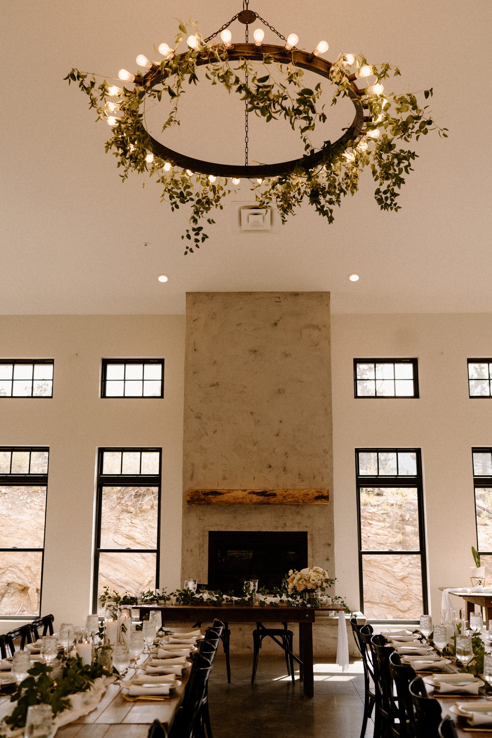 A large chandelier decorated in greenery hangs above the reception at North Star Gatherings in Idaho Springs, CO