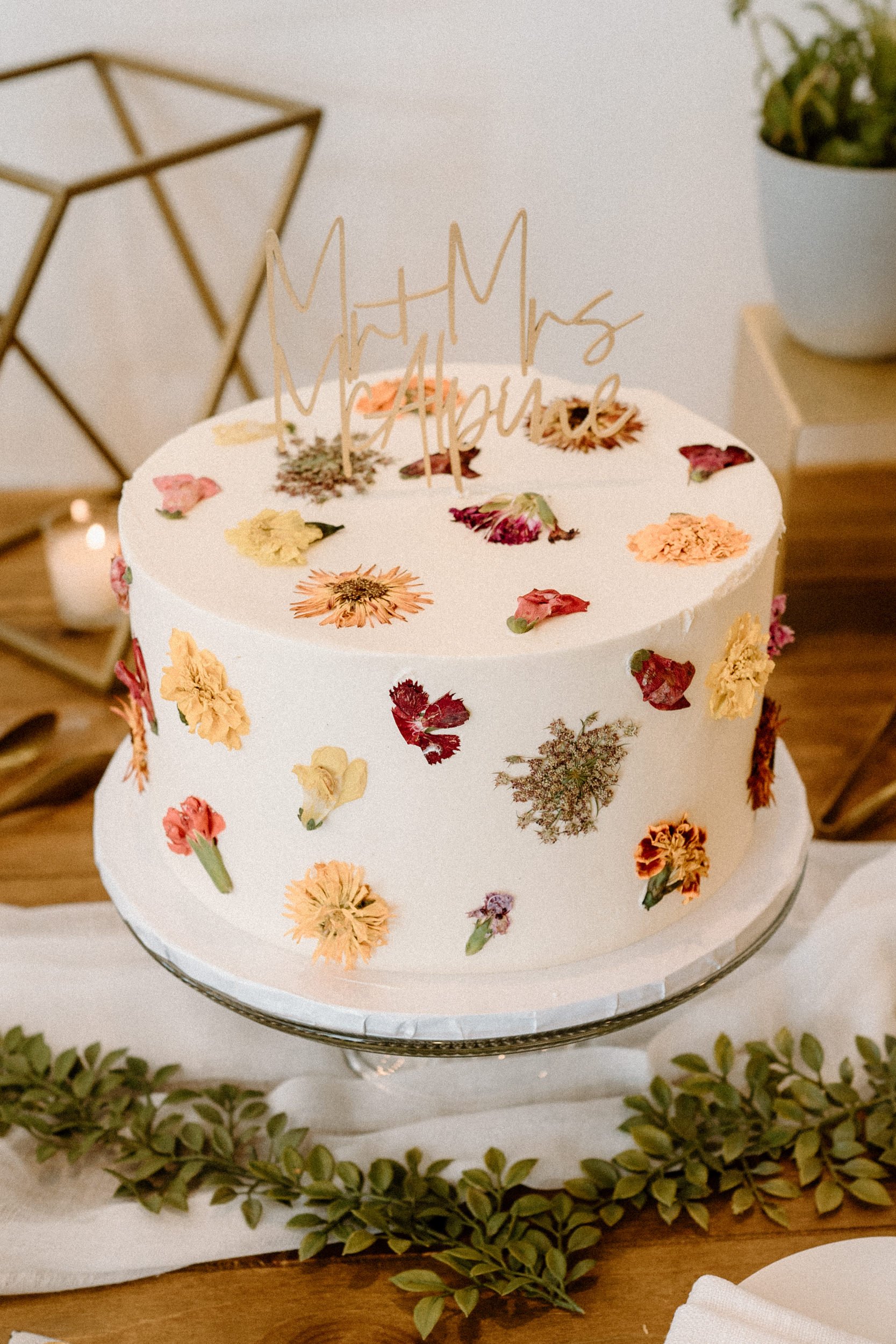 A white wedding cake decorated with colorful flower petals