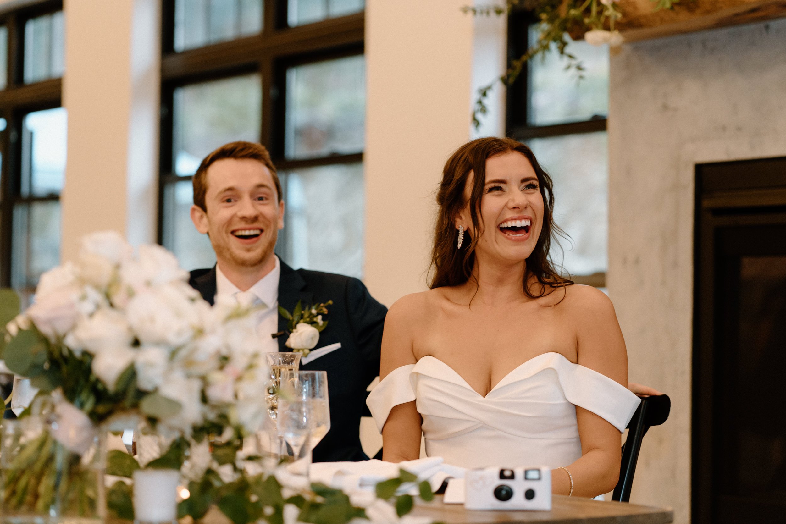 The bride and groom laugh during the toasts