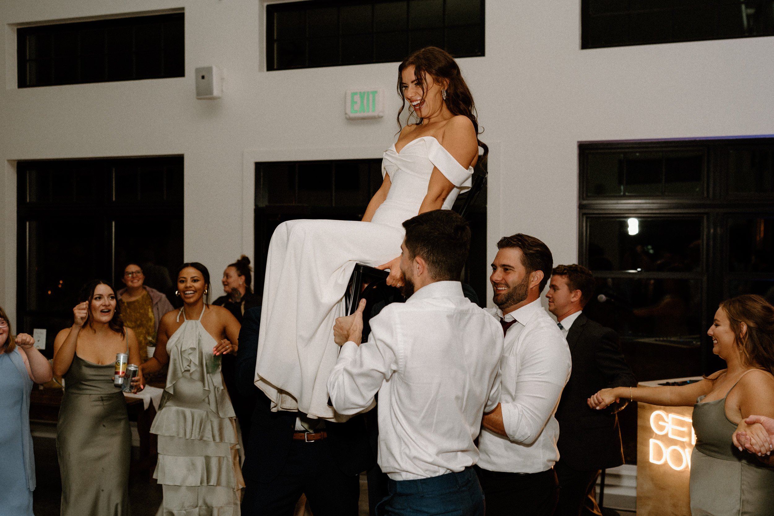 The wedding guests lift the bride in a chair