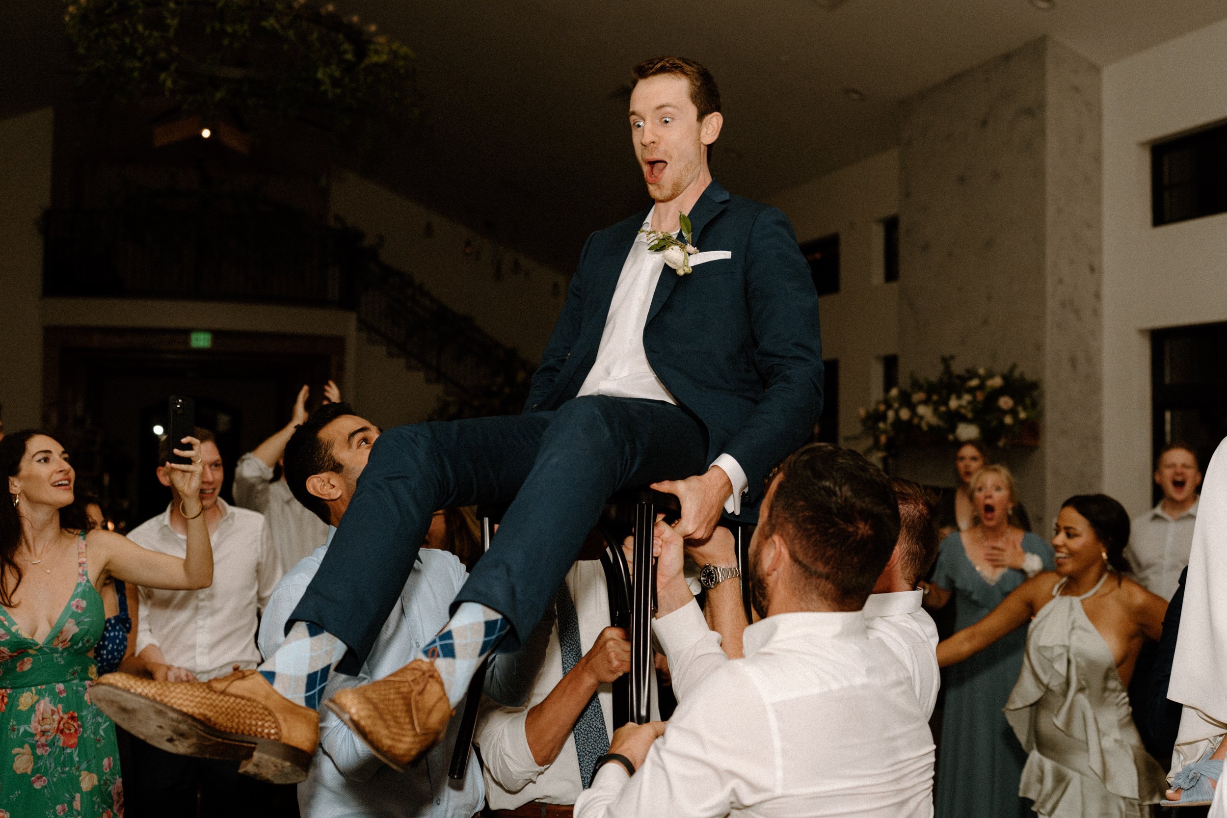The wedding guests lift the groom in a chair