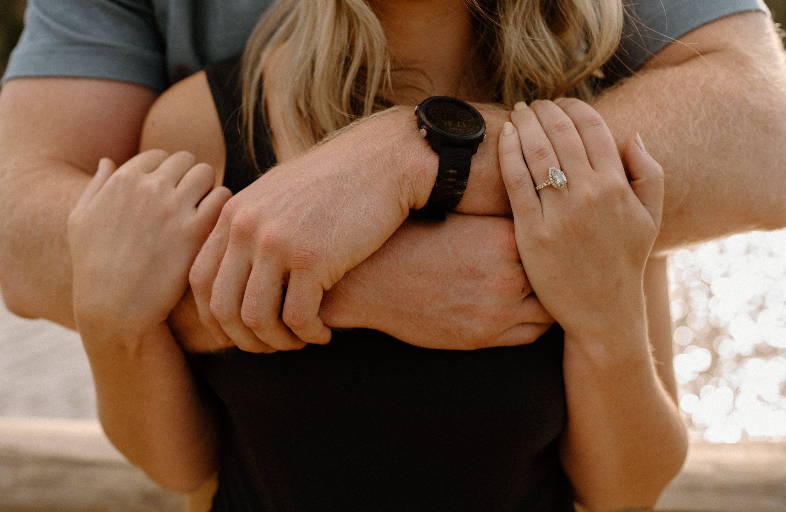 Close up of man's arms enveloping woman from behind