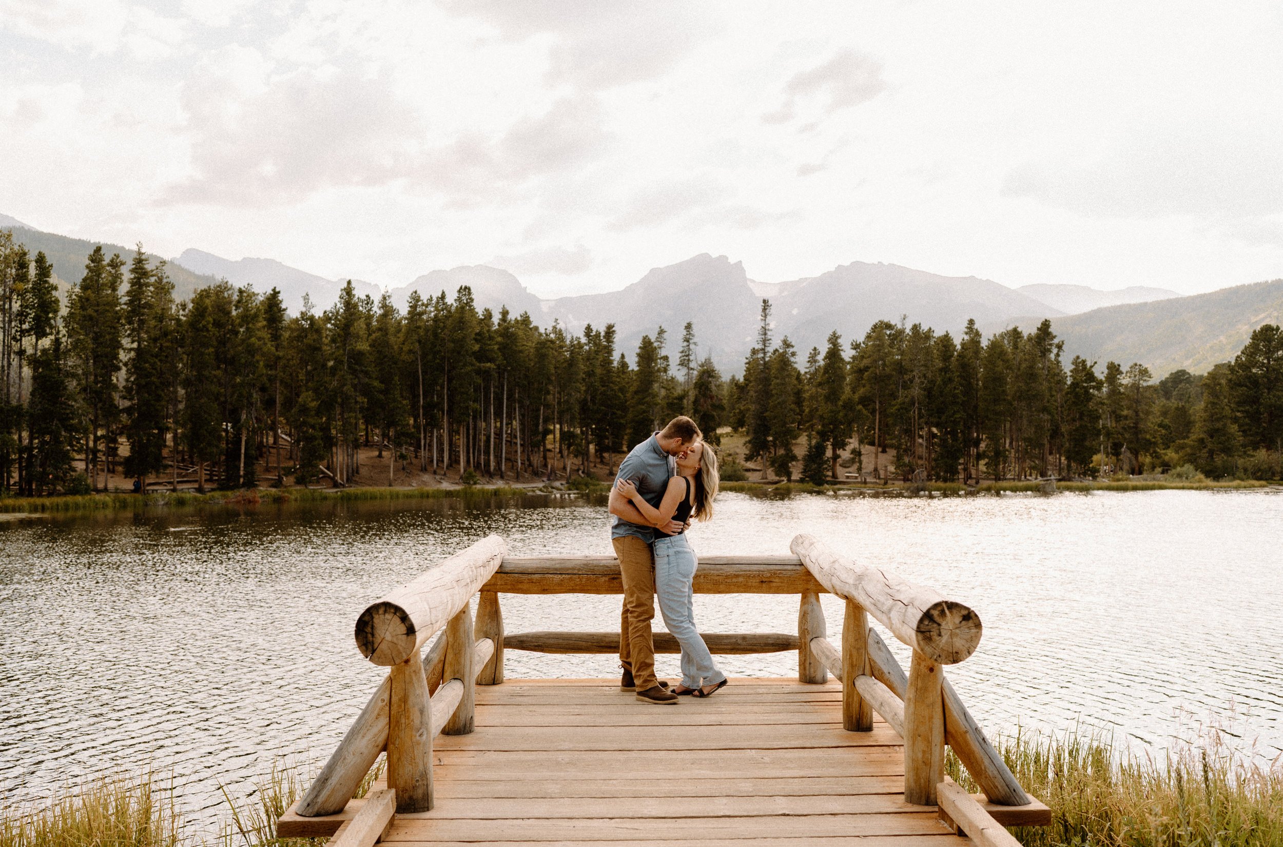 Man and woman kiss on dock on Sprague Lake at Rocky Mountain National Park