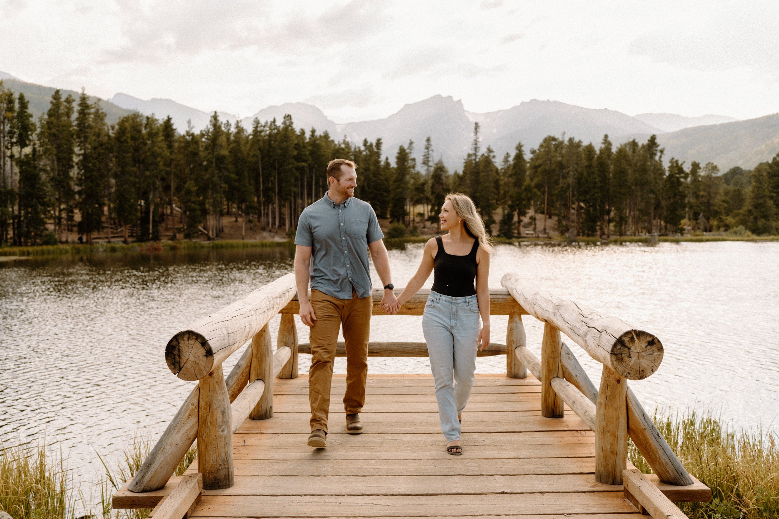 Man and woman hold hands on dock Sprague Lake at Rocky Mountain National Park