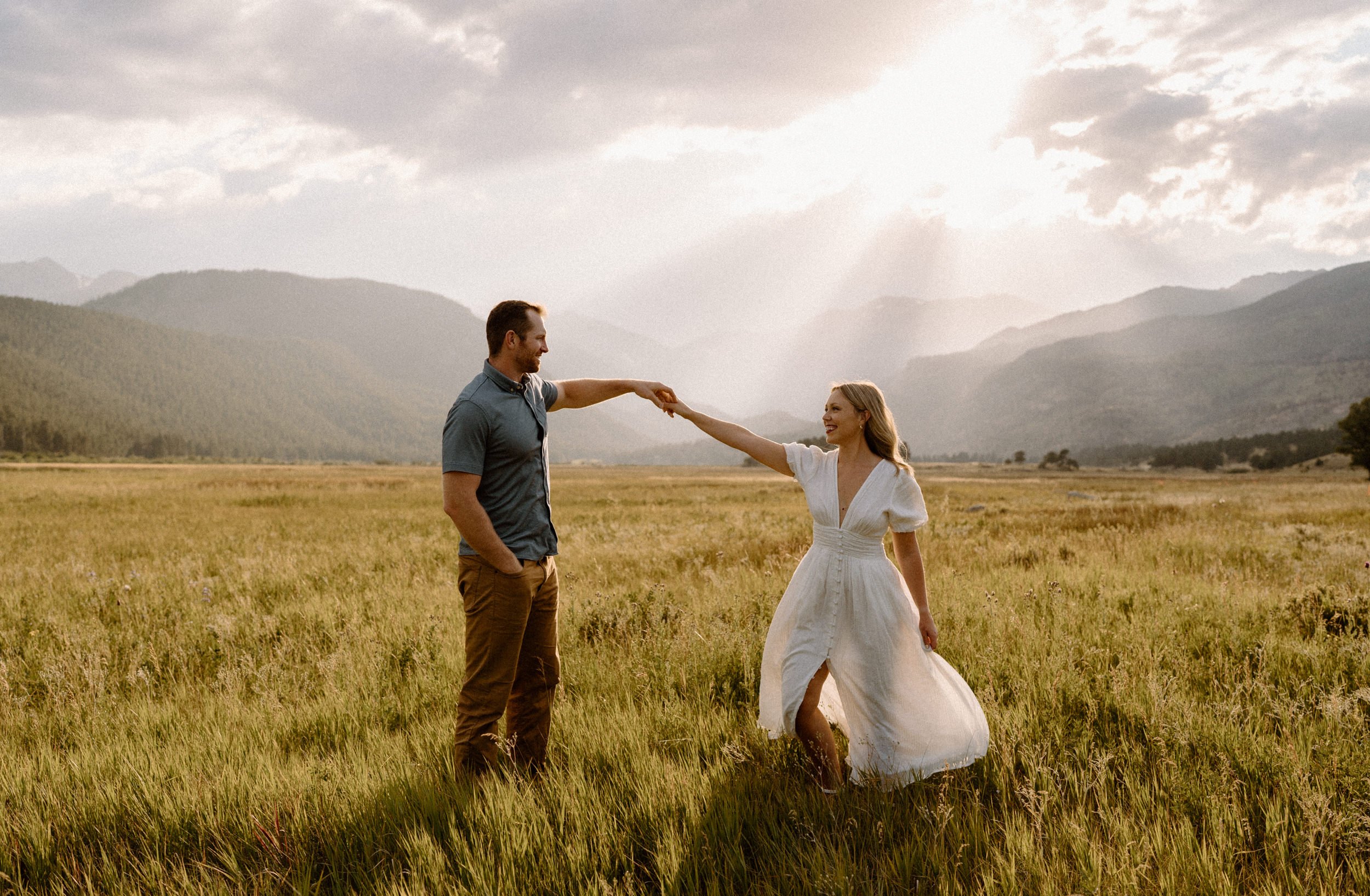 Man twirls woman in a meadow in Rocky Mountain National Park