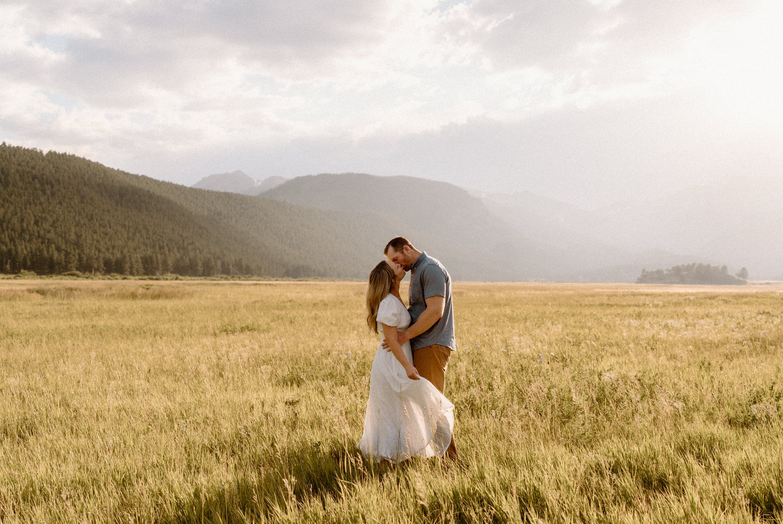 Man and woman kiss in a meadow in Rocky Mountain National Park