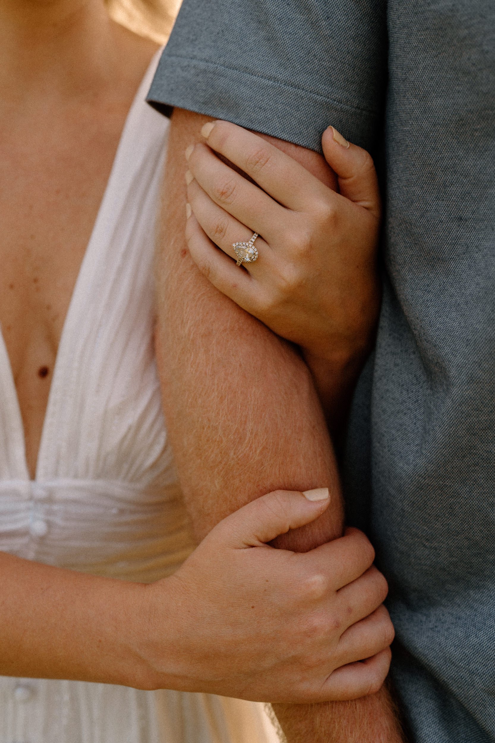Close up image of woman wrapping her arms around man showcasing her engagement ring