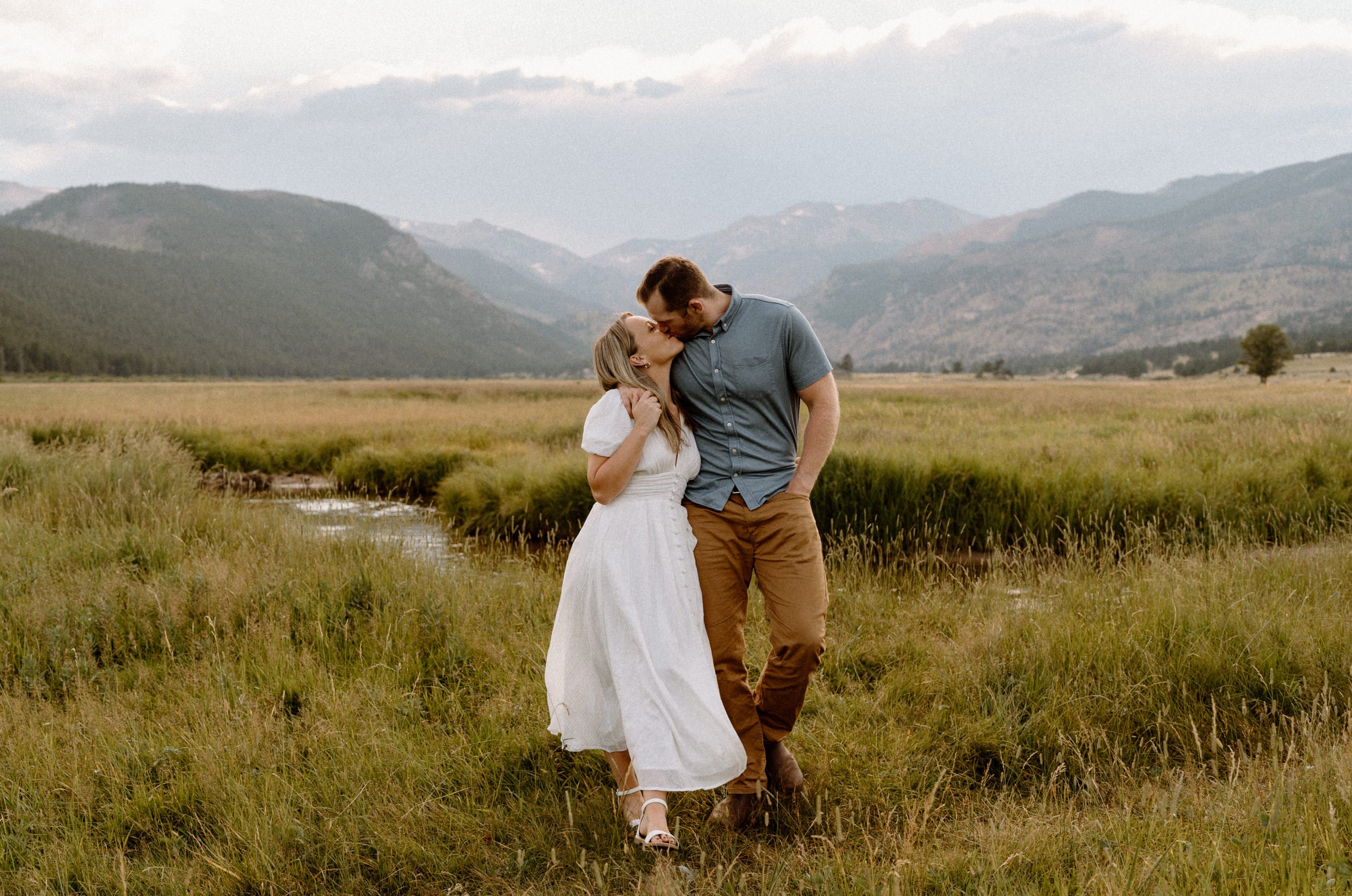 Man and woman kiss as they walk along the creek in Rocky Mountain National Park