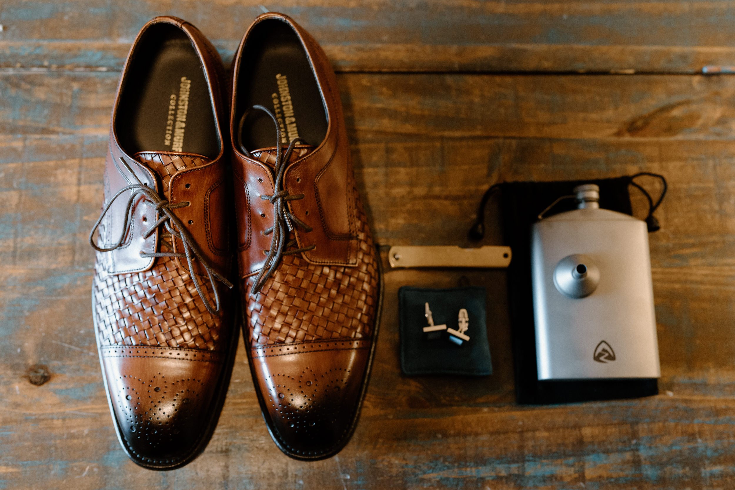 Close up of the groom's shoes, cufflinks, and flask