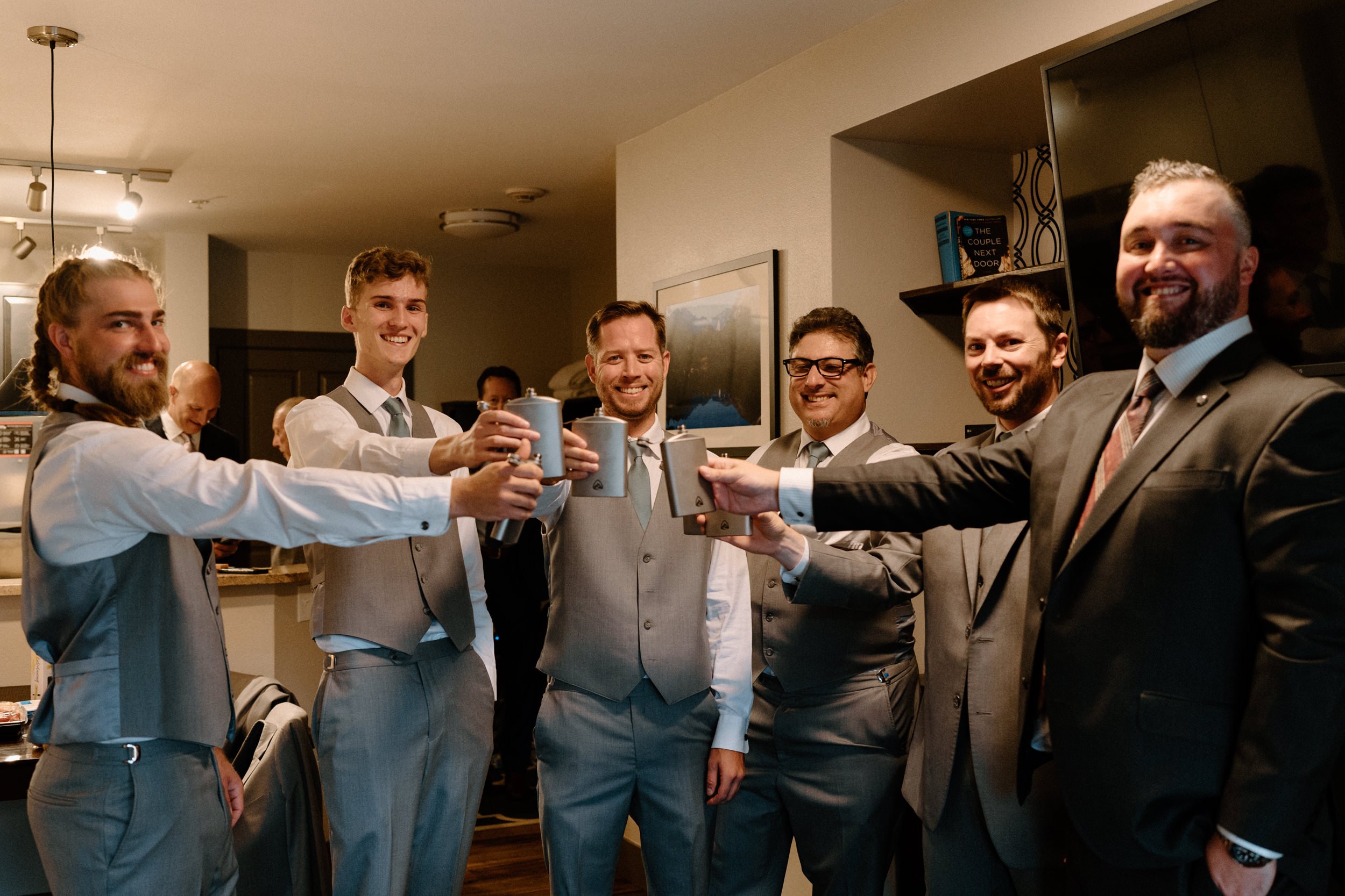 The groomsmen hold up their matching flasks in a toast